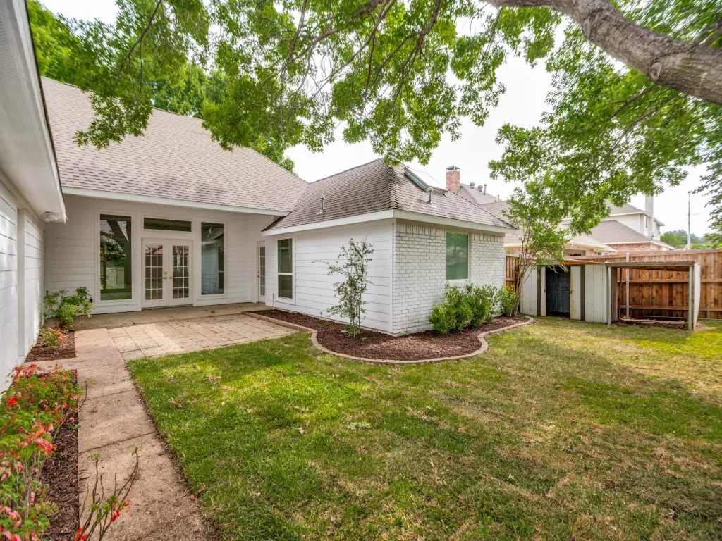 Rear exterior featuring white siding, a paved patio, and a grass lawn
