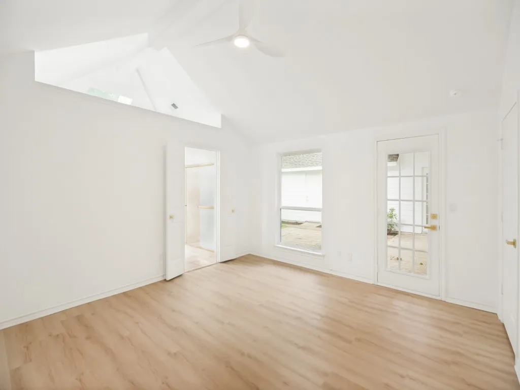 Vaulted ceilings with an architectural accent opening, wood-finish flooring, a ceiling fan, and a glass-paneled exterior door