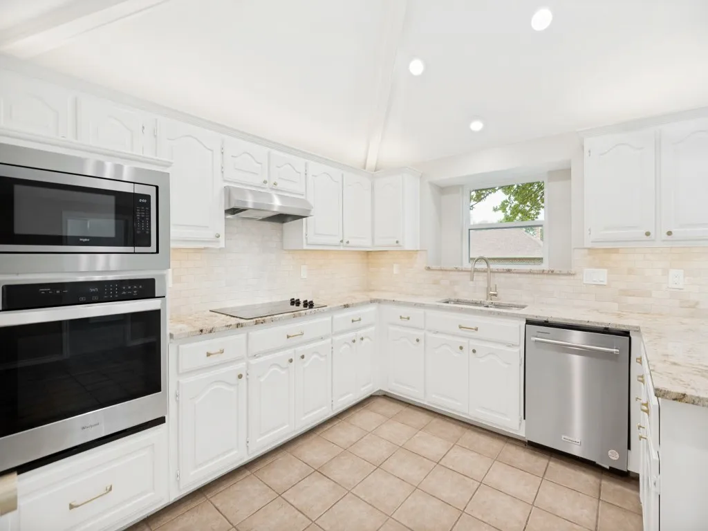 Kitchen featuring white cabinetry, granite countertops, tile backsplash, built-in stainless steel appliances, and recessed lighting