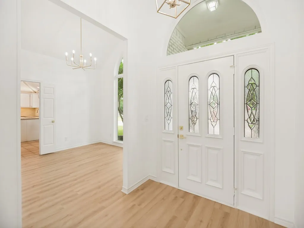 Grand entryway featuring a double door with decorative glass inserts and an arched transom window