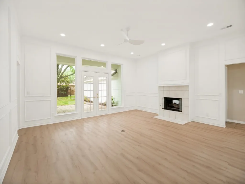Spacious interior featuring wood-finish flooring, recessed lighting, and white wainscoting