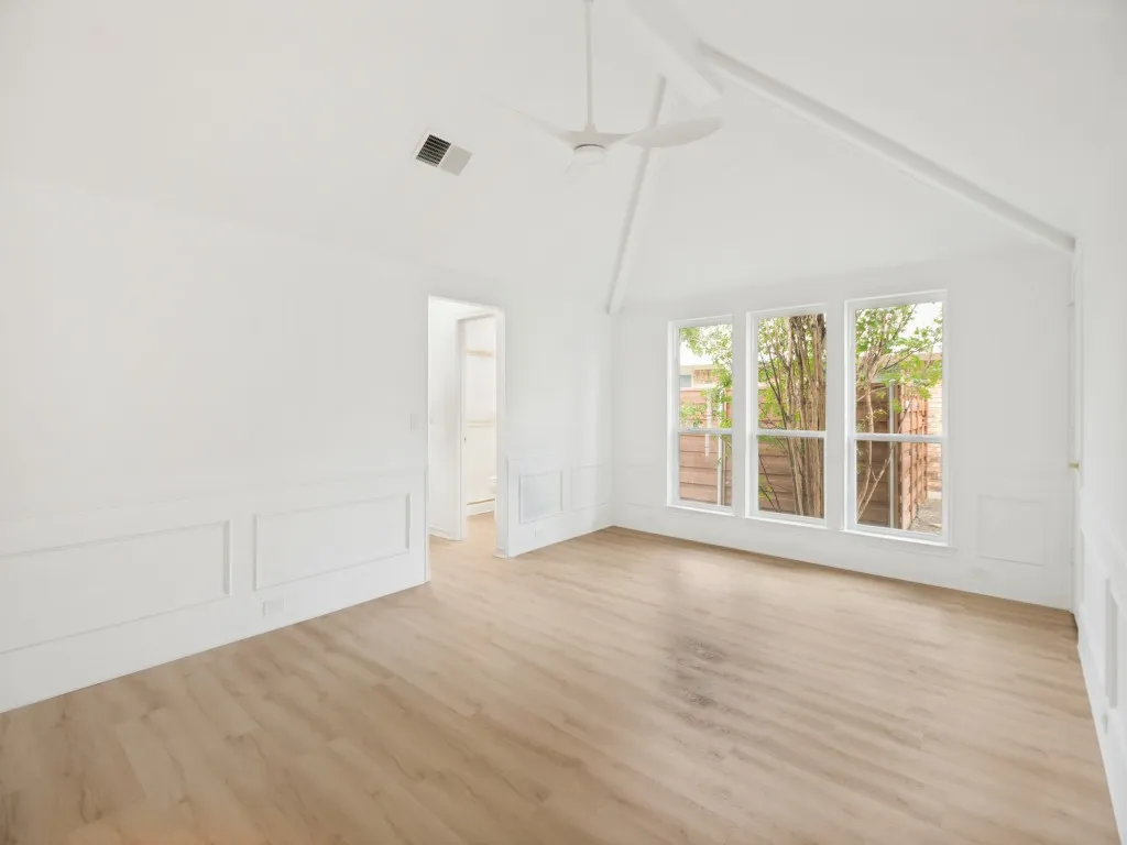 Vaulted ceiling with exposed beam, modern ceiling fan, and light wood-finish flooring
