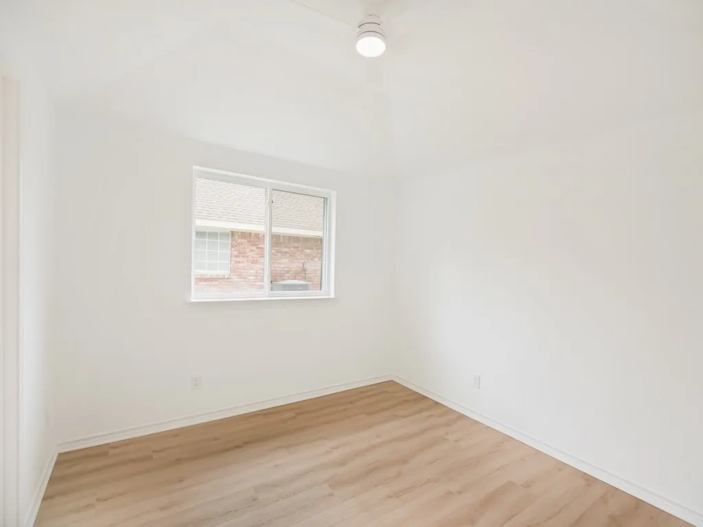 Room featuring neutral wall finishes, a single-pane window, wood-finish flooring, a white baseboard, and a flush-mount ceiling light