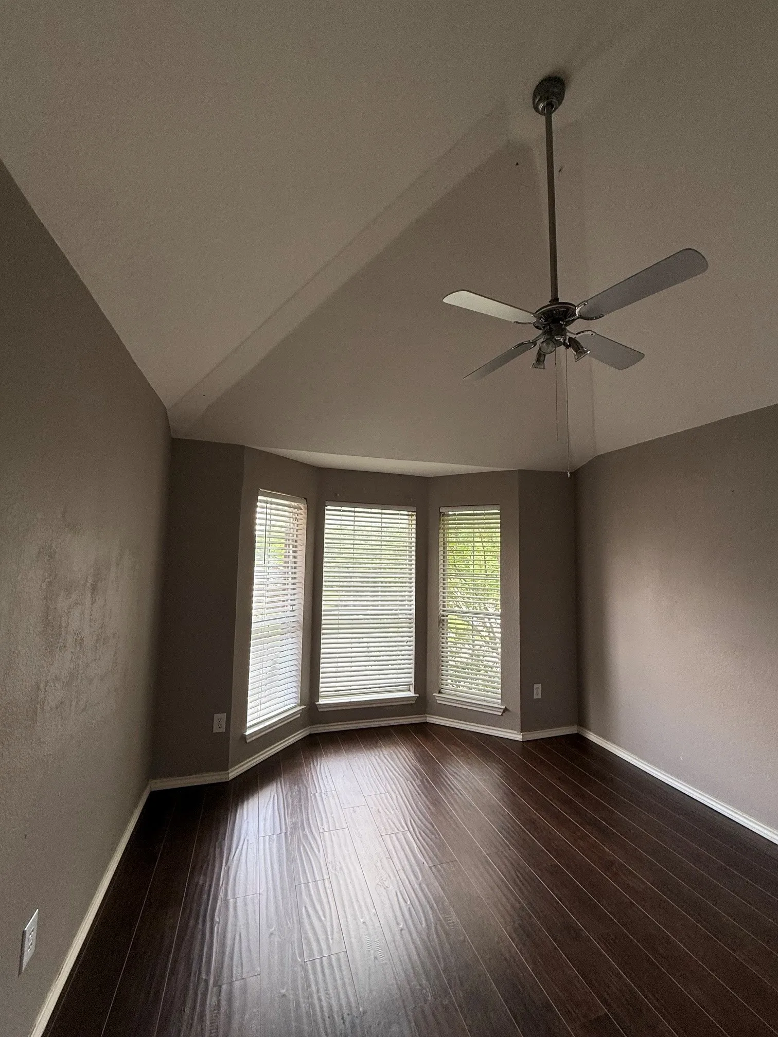 Bedroom featuring dark wood-finish flooring, a bay window with blinds, and a vaulted ceiling with a ceiling fan