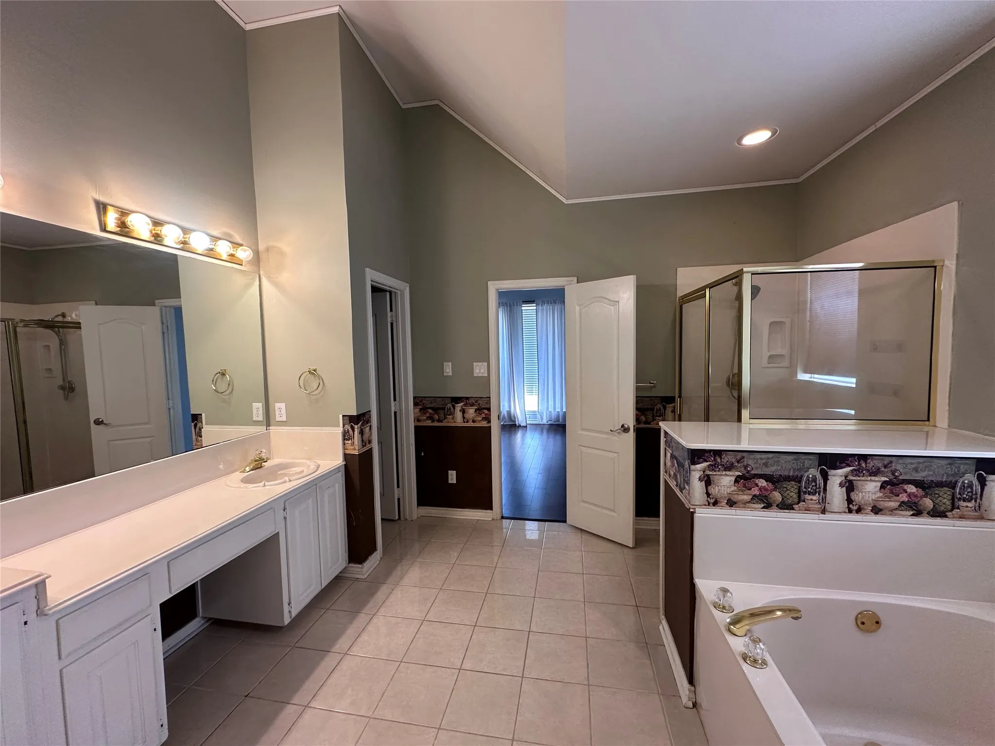 Spacious bathroom featuring a built-in tub, a separate glass-enclosed shower, dual vanities with integrated sinks, and tiled flooring