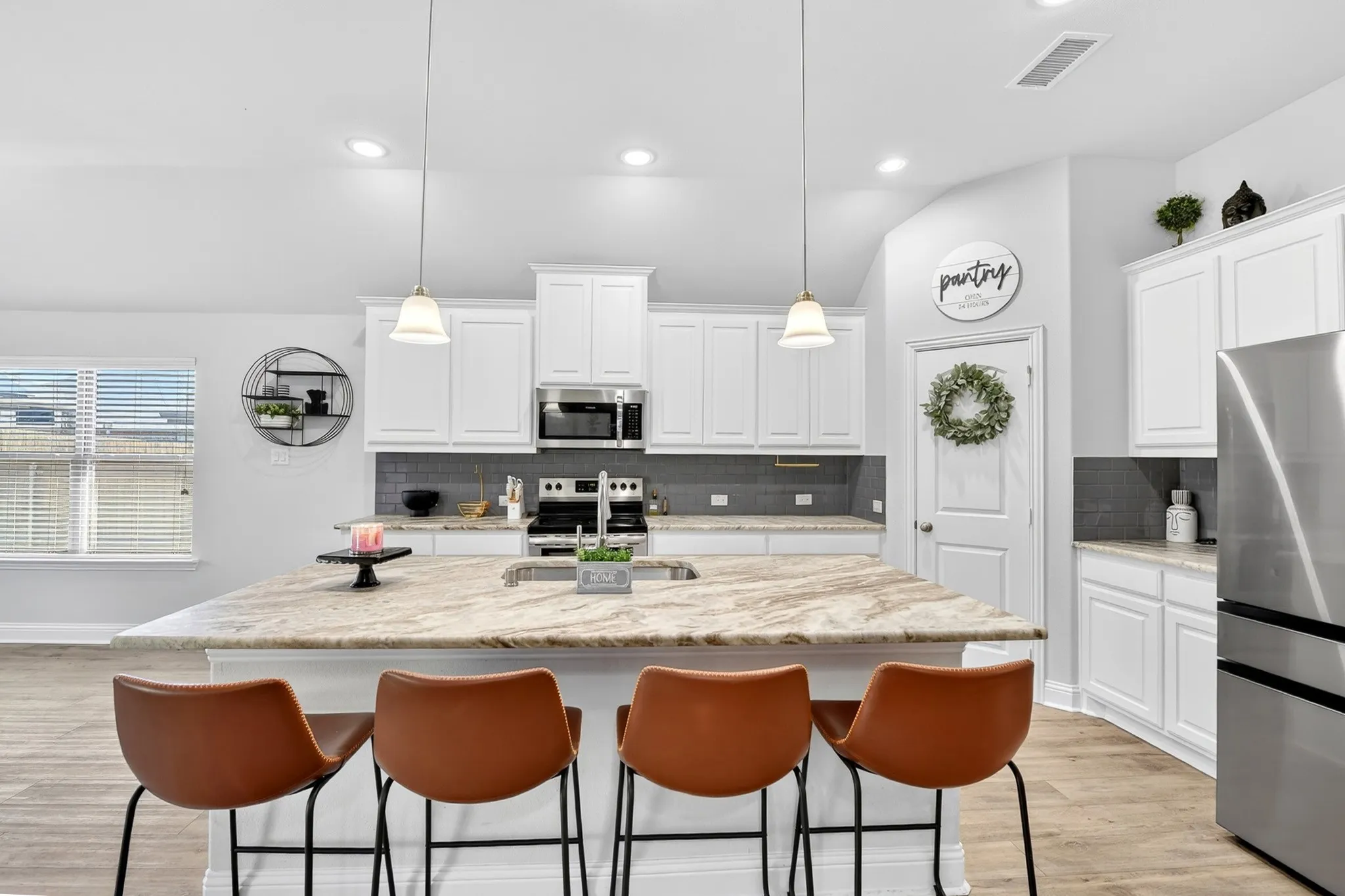 Open-concept kitchen featuring an oversized island with ample counter space, white cabinetry, stainless steel appliances, a tiled backsplash, and recessed lighting