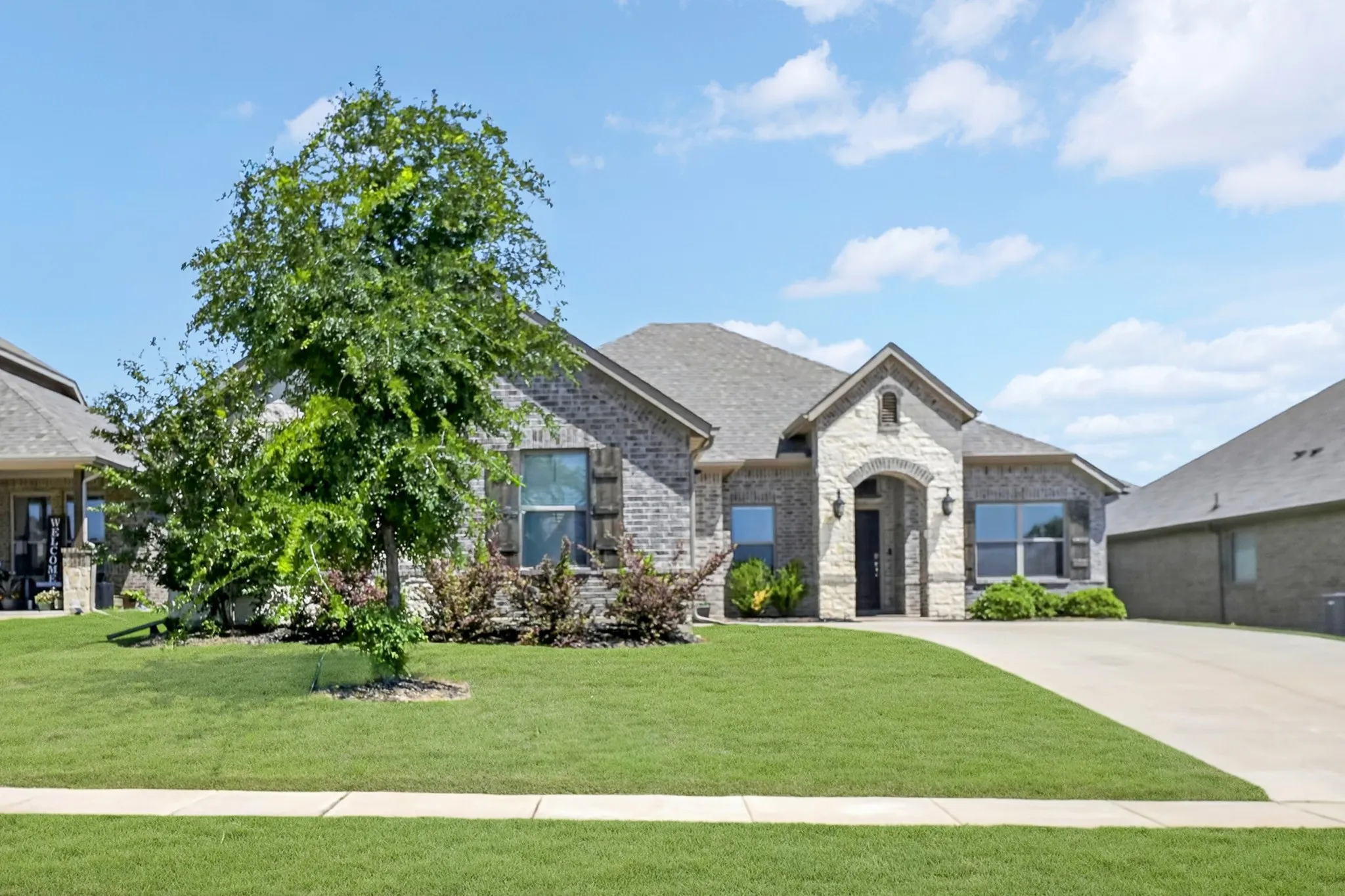 Brick and stone facade residence featuring an arched entryway with decorative sconces