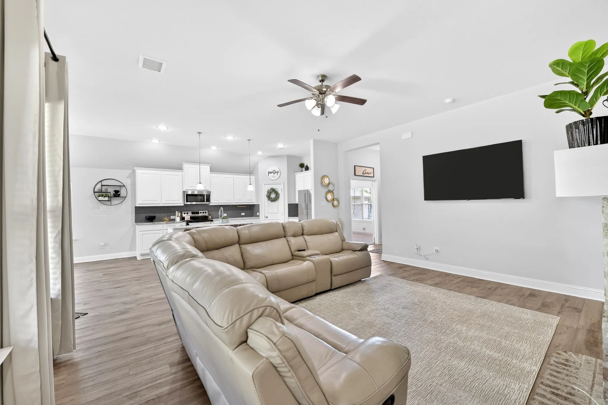 Open-concept living space featuring wood-finish flooring, recessed lighting, and a ceiling fan