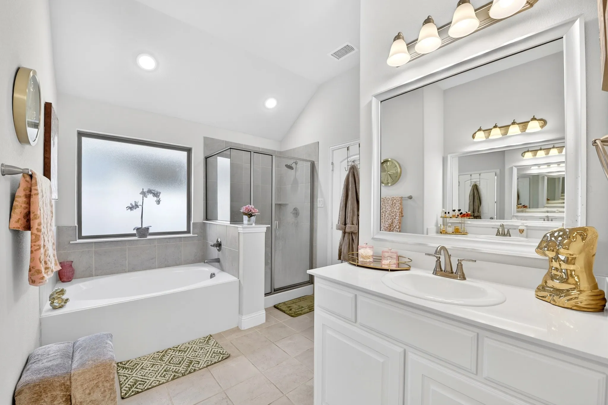 Bathroom featuring a white soaking tub, a separate glass-enclosed shower, and a vanity with an integrated sink