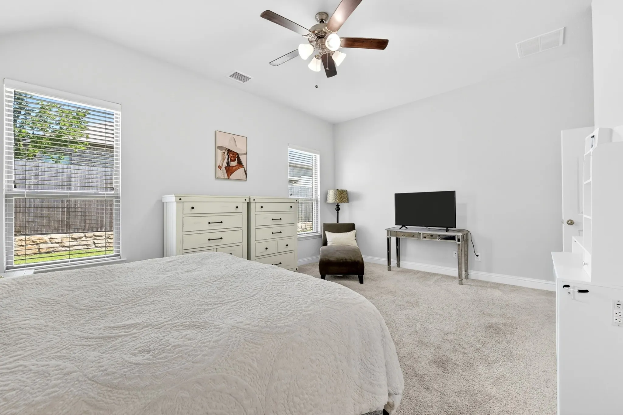 Carpeted interior space featuring a vaulted ceiling with a ceiling fan, white walls, and white window blinds