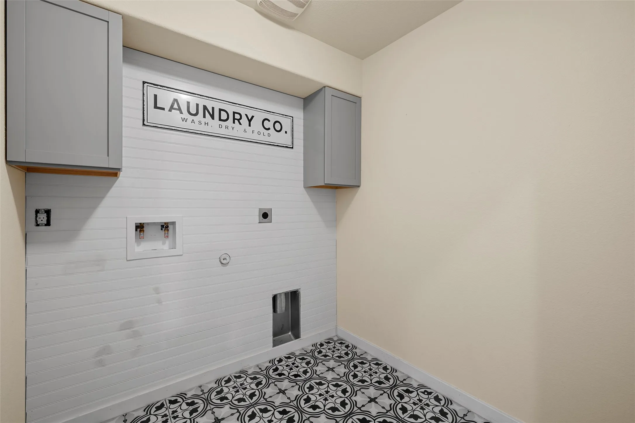 Dedicated laundry area featuring patterned tile flooring and white shiplap-style wall paneling