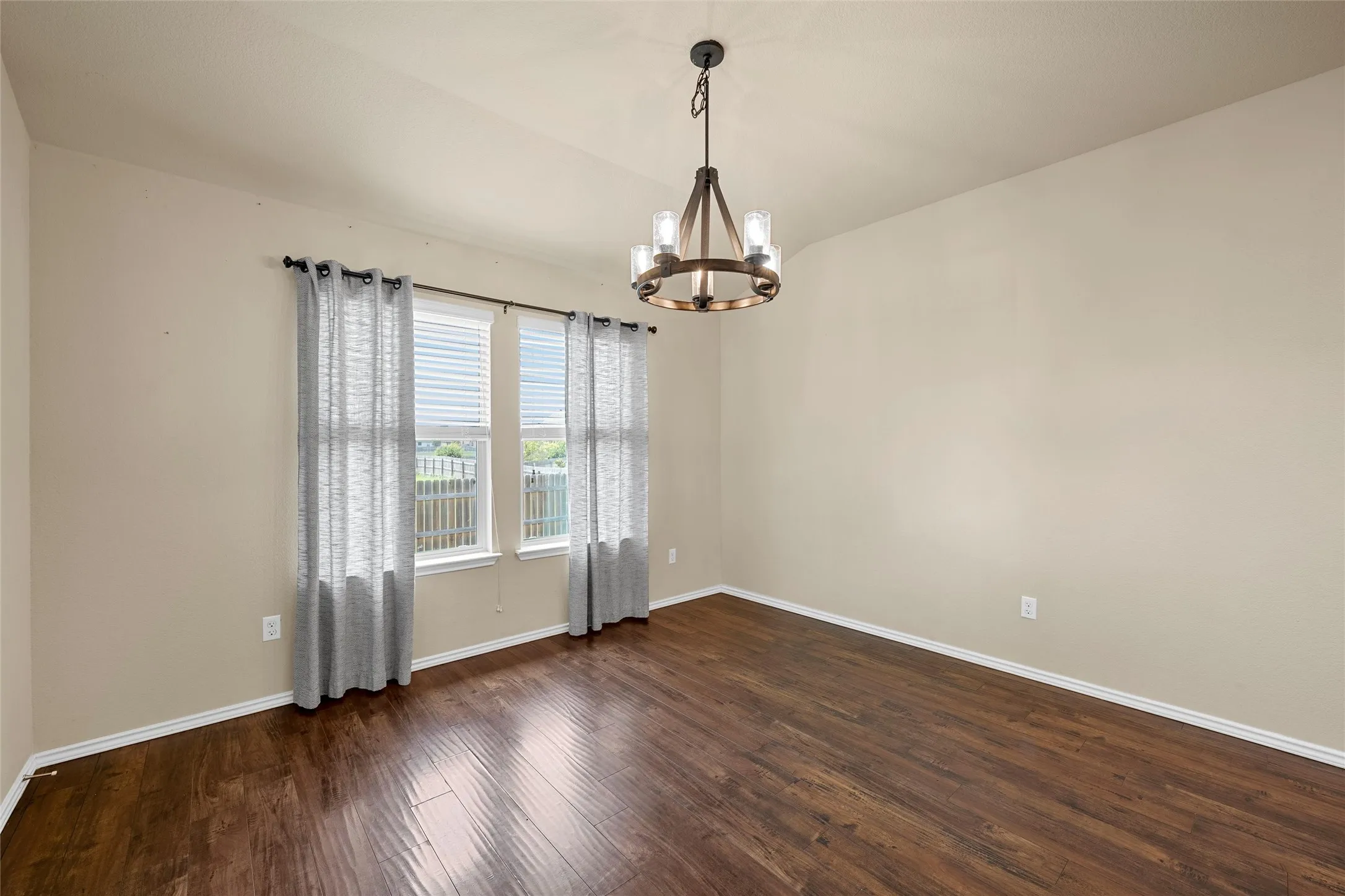 Open-concept room featuring wood-finish flooring, neutral wall tones, and a contemporary chandelier