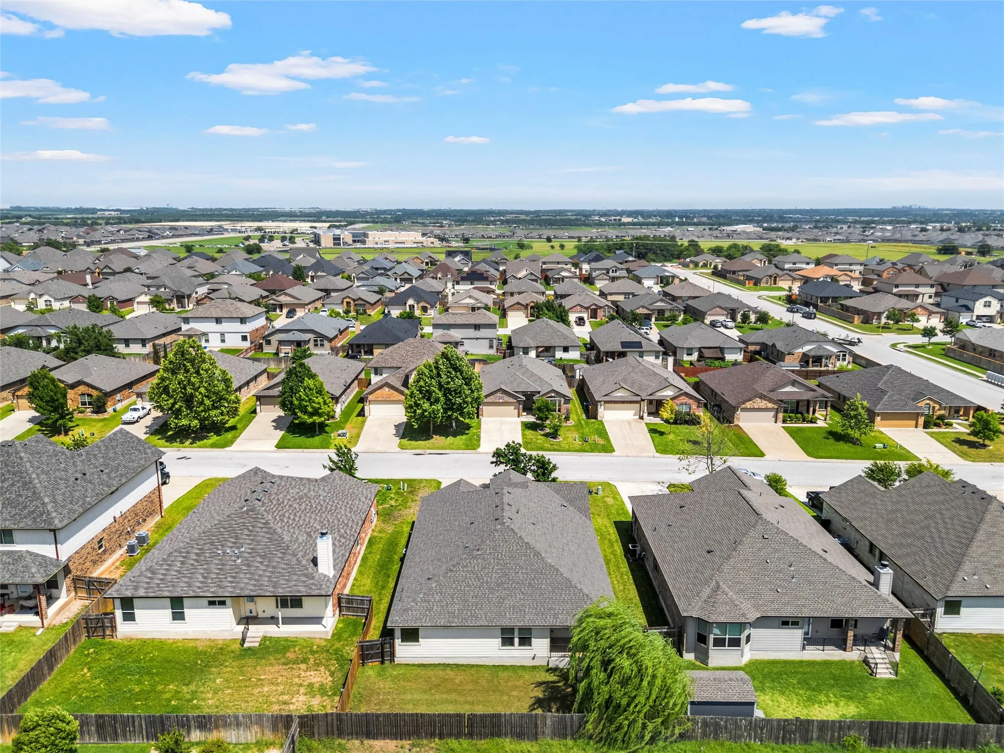 Residential neighborhood featuring a consistent architectural style, mature trees, and individual fenced backyards