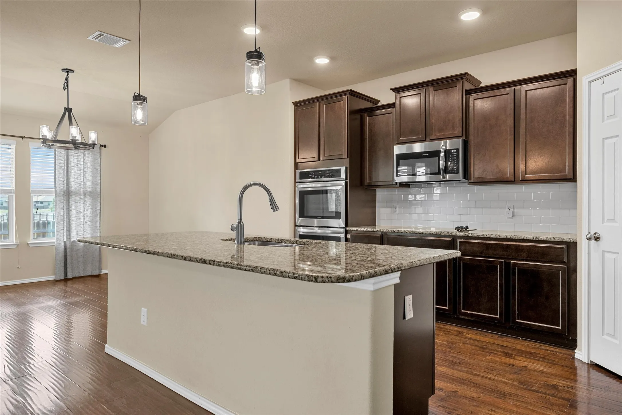 Kitchen island featuring a single-basin sink, gooseneck faucet, and granite countertop