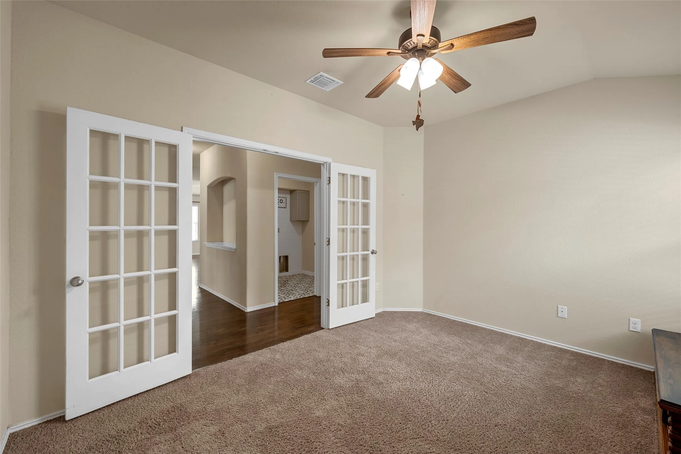 Room featuring twin French doors, vaulted ceiling, and a ceiling fan with light fixture