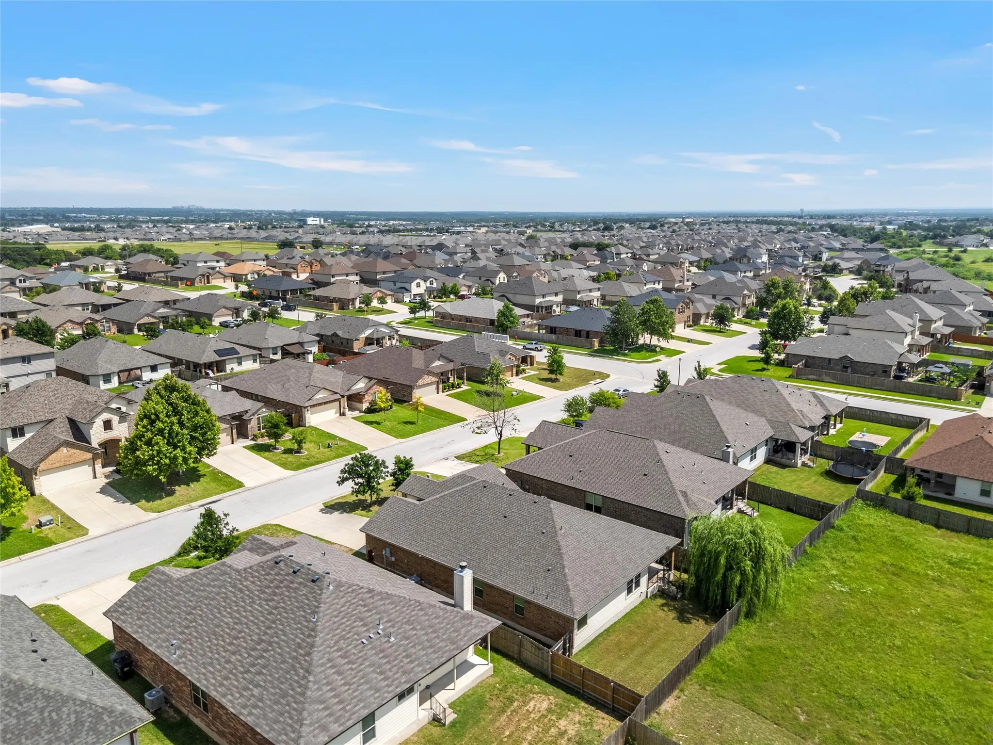 Aerial perspective of a residential neighborhood with uniformly designed homes featuring shingle roofs, paved streets, and green lawns