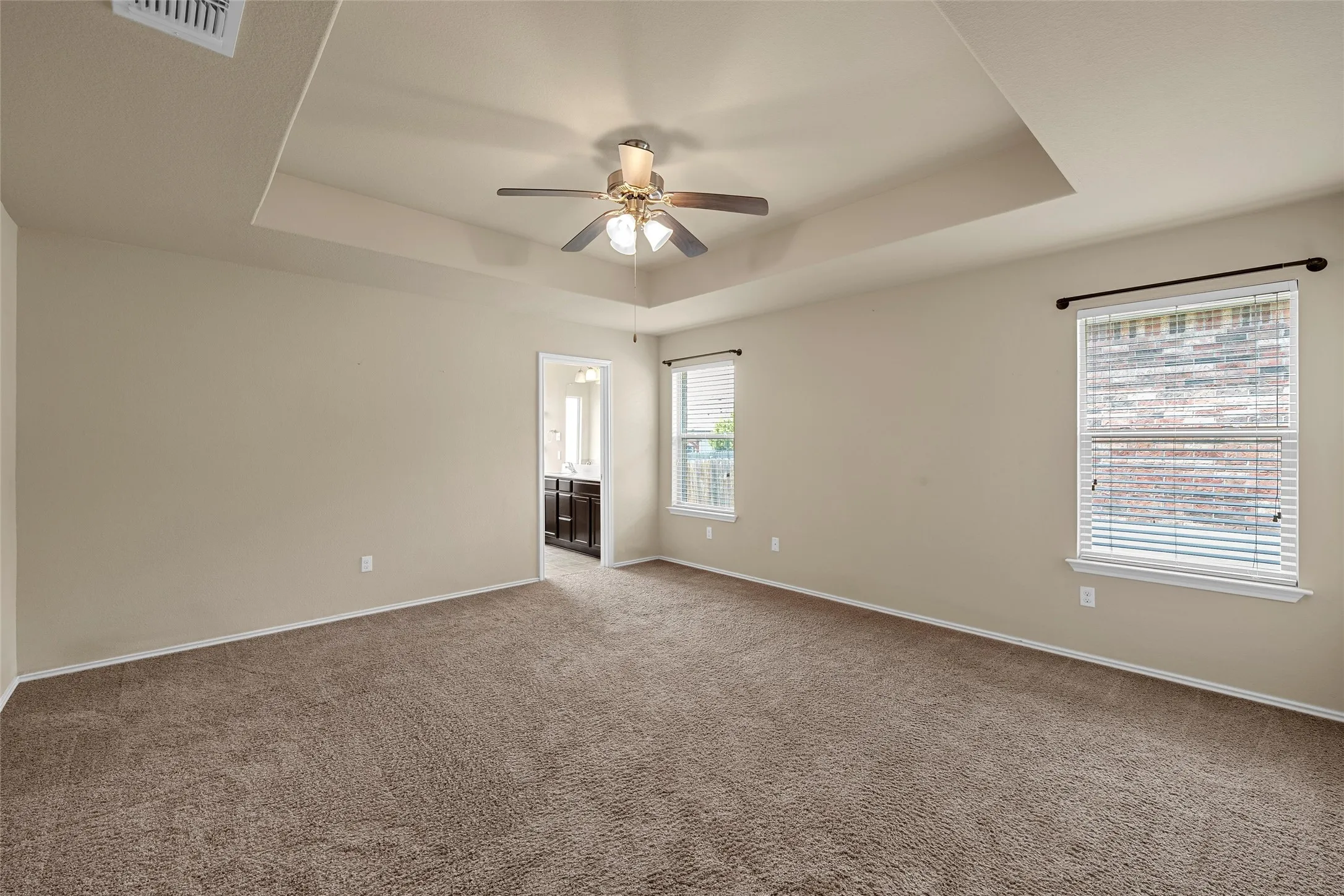 Carpeted room with a tray ceiling and ceiling​​‌​​​​‌​​‌‌​‌‌​​​‌‌​‌​‌​‌​​​‌​​ fan