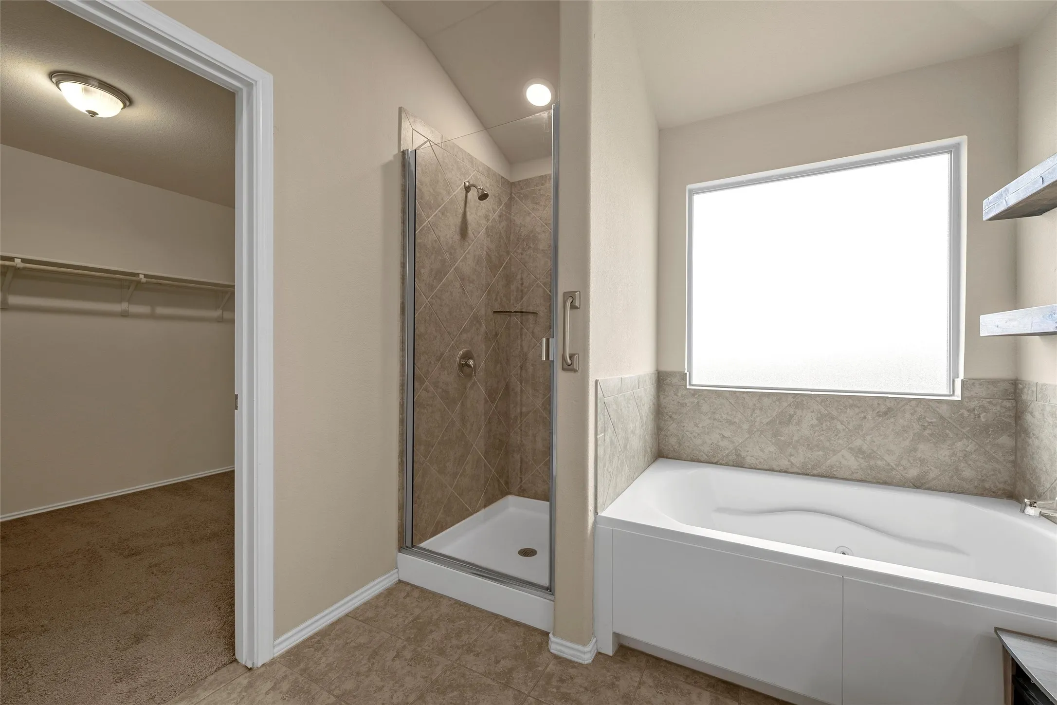 Bathroom featuring a built-in tub, separate shower with glass enclosure, wall-mounted shelving, and a frosted window