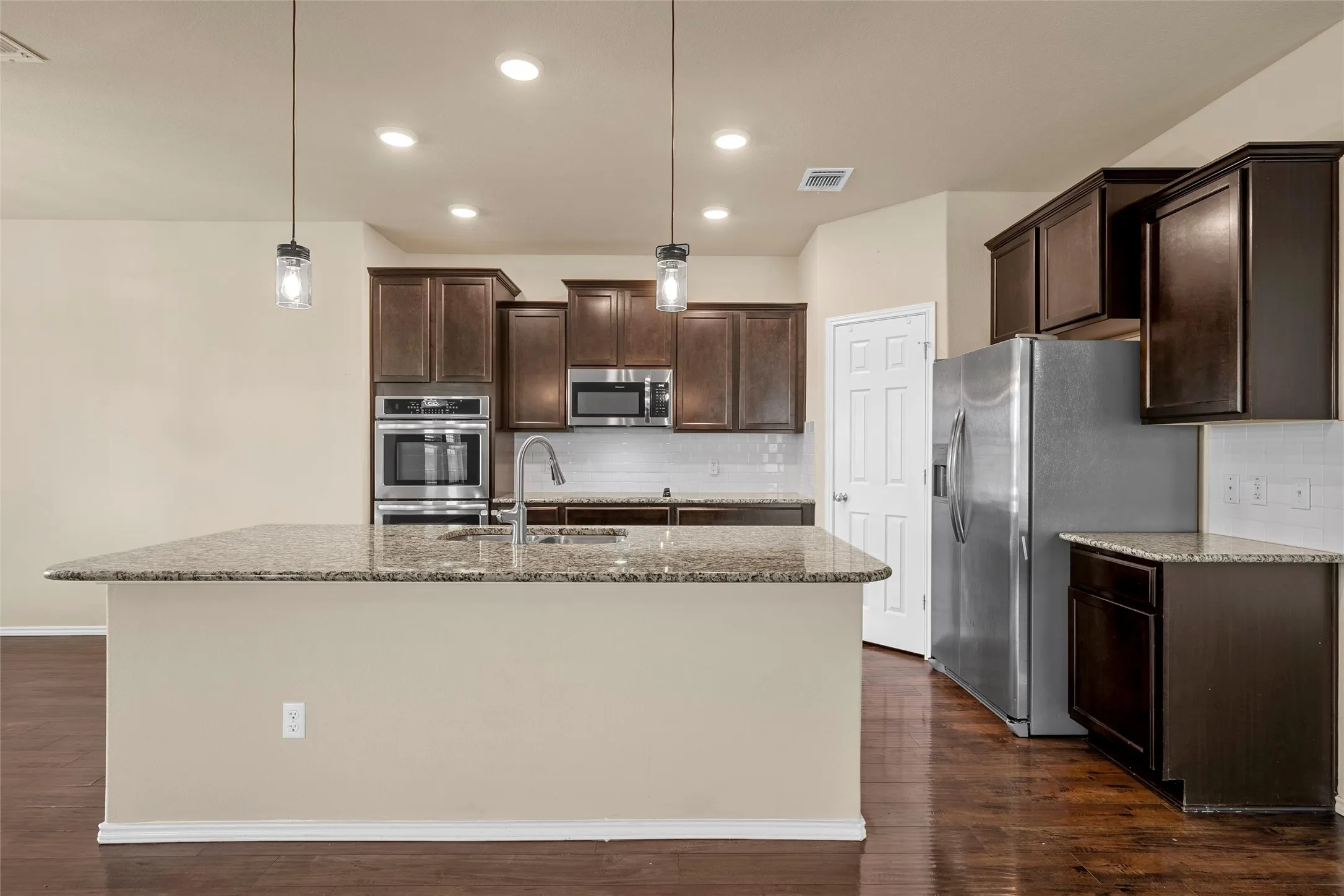 Kitchen island with a granite-style countertop and undermount sink