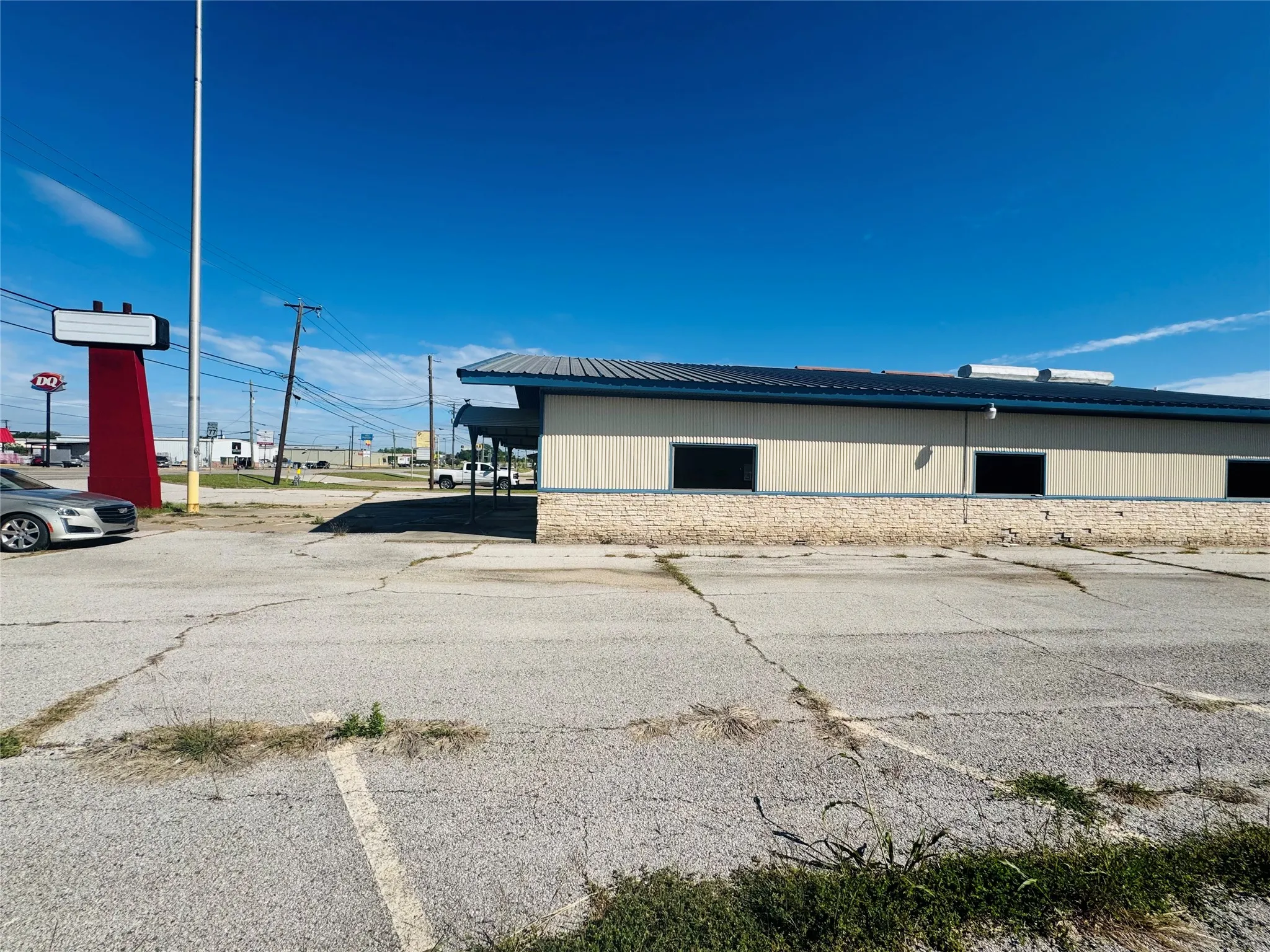 Commercial building featuring a light-colored exterior with a stone-finish base, dark-framed windows, and a dark-colored roof