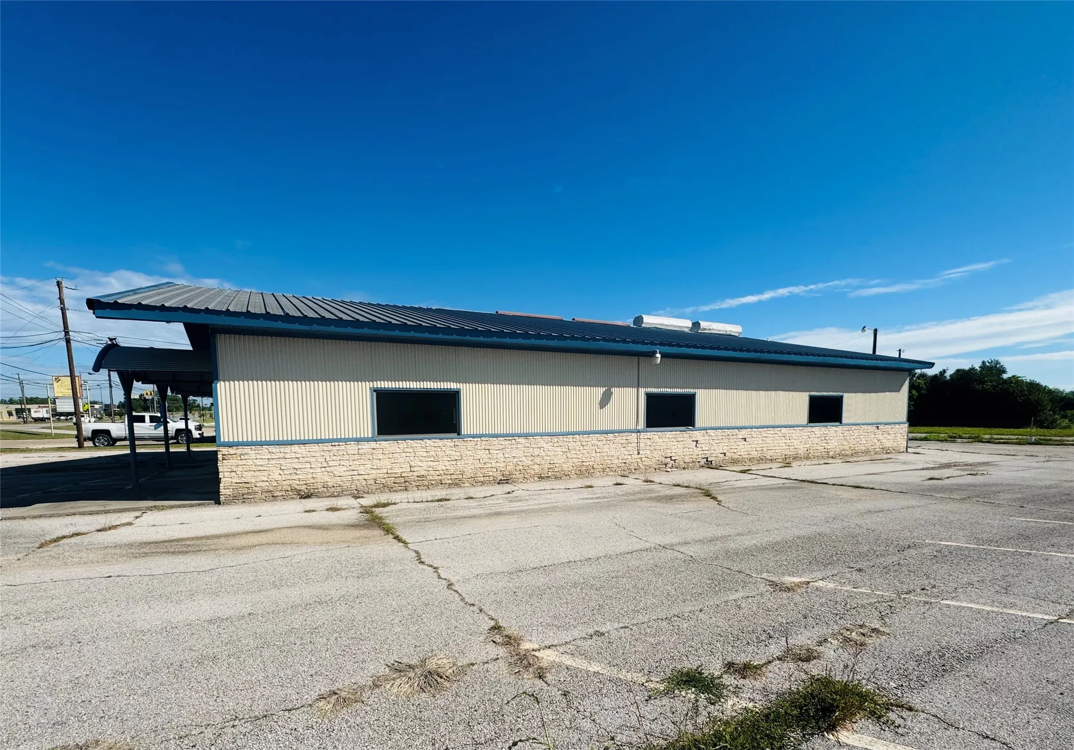 Commercial building featuring a metal roof, corrugated siding, and a stone-clad base