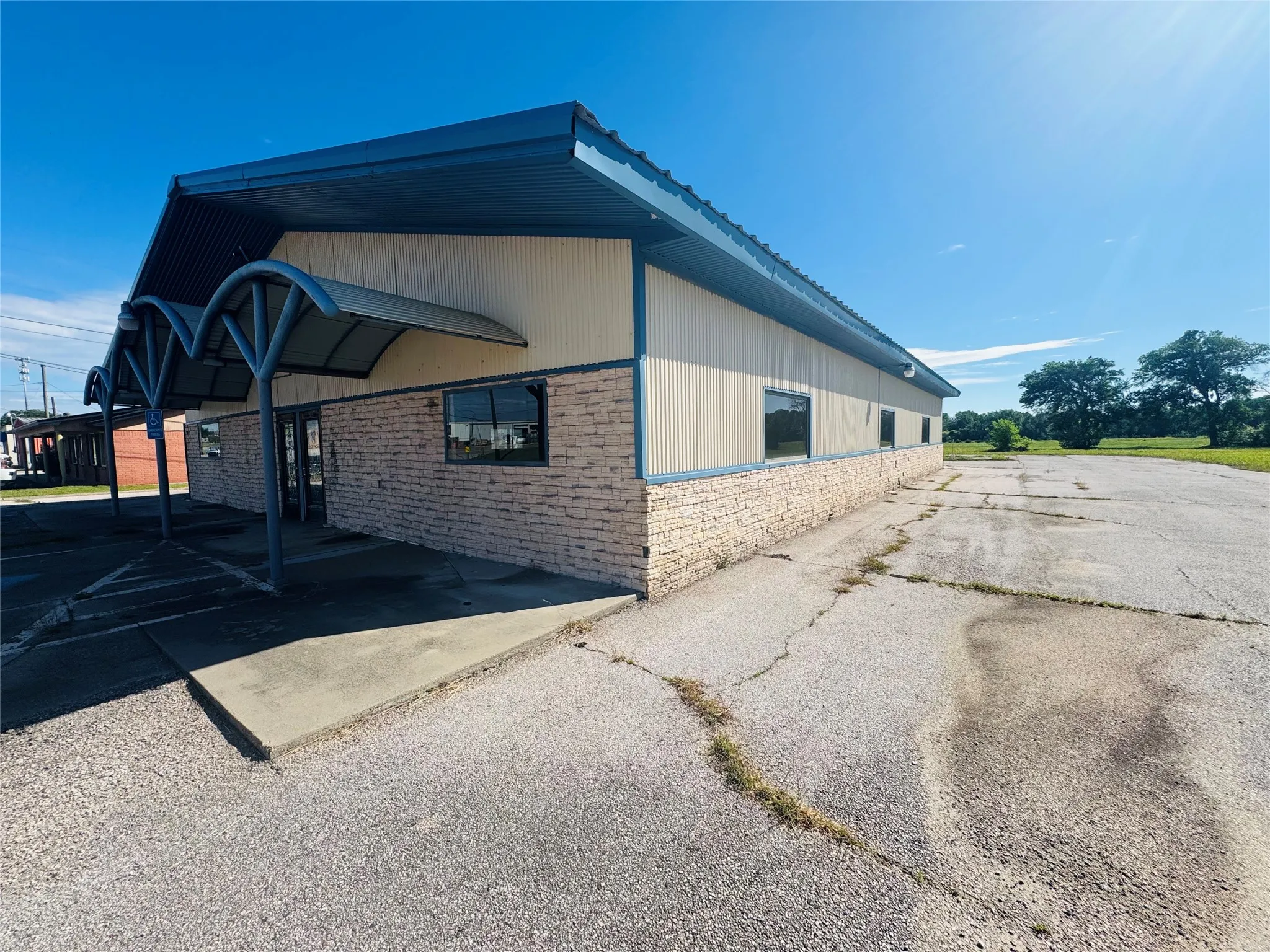 Commercial building featuring a brick facade, blue metal roof, and multiple window openings