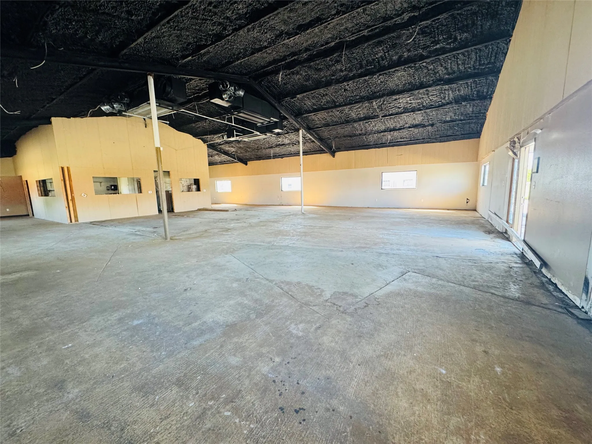 Spacious open-concept interior featuring concrete flooring, high ceilings, and exposed structural beams