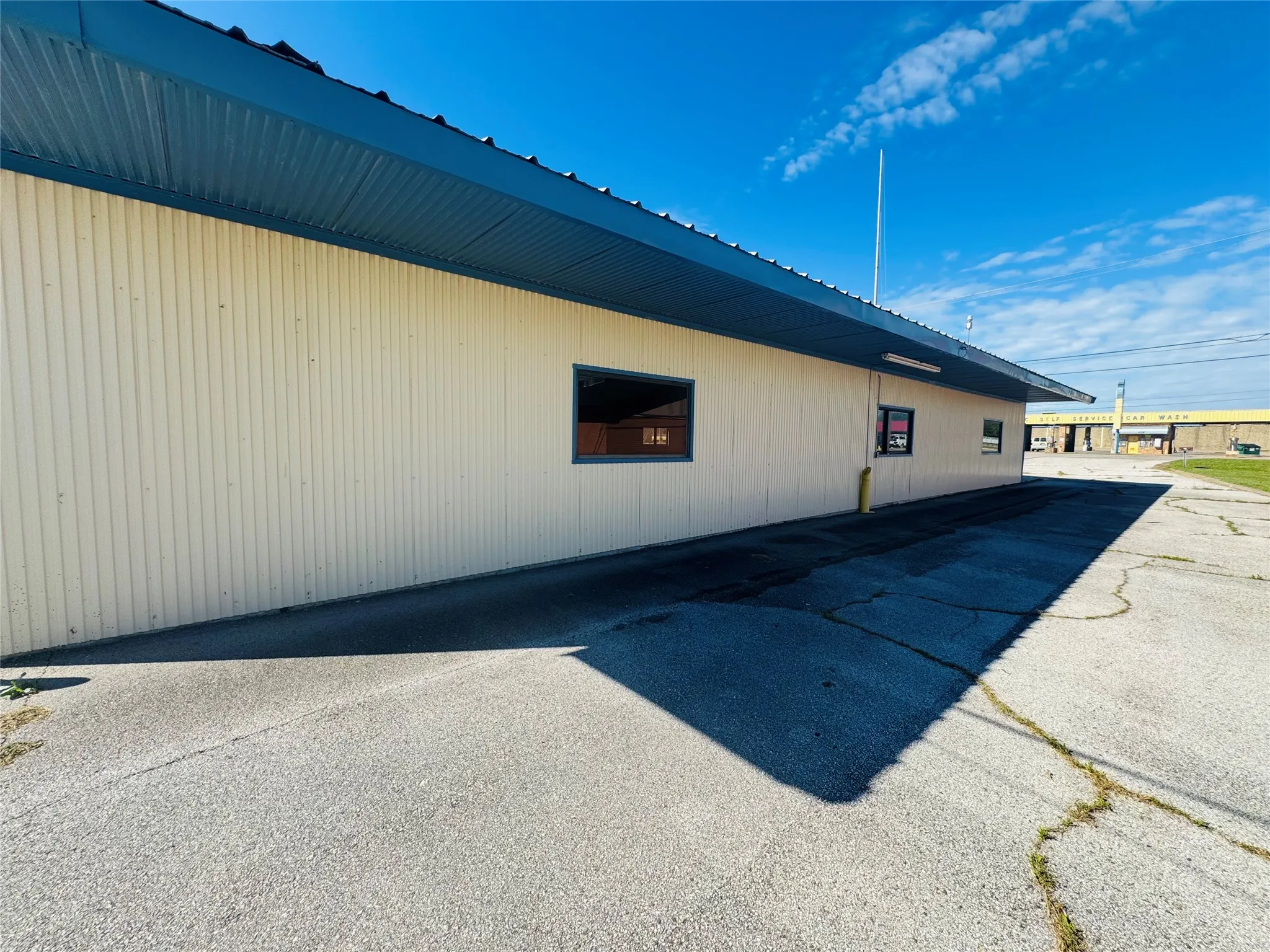 Commercial building featuring vertical panel siding, a dark blue corrugated metal roof, and an extended overhang