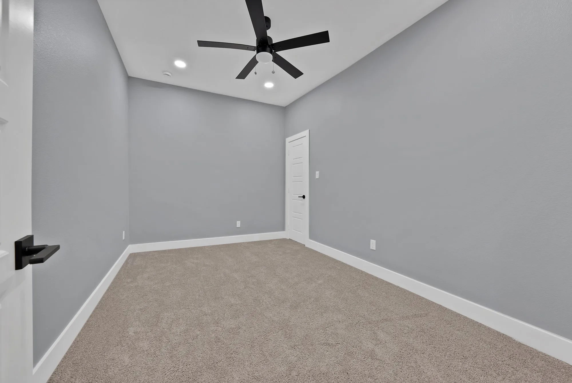 Room featuring light gray walls, plush carpeting, a black ceiling fan with integrated lighting, and recessed ceiling lights