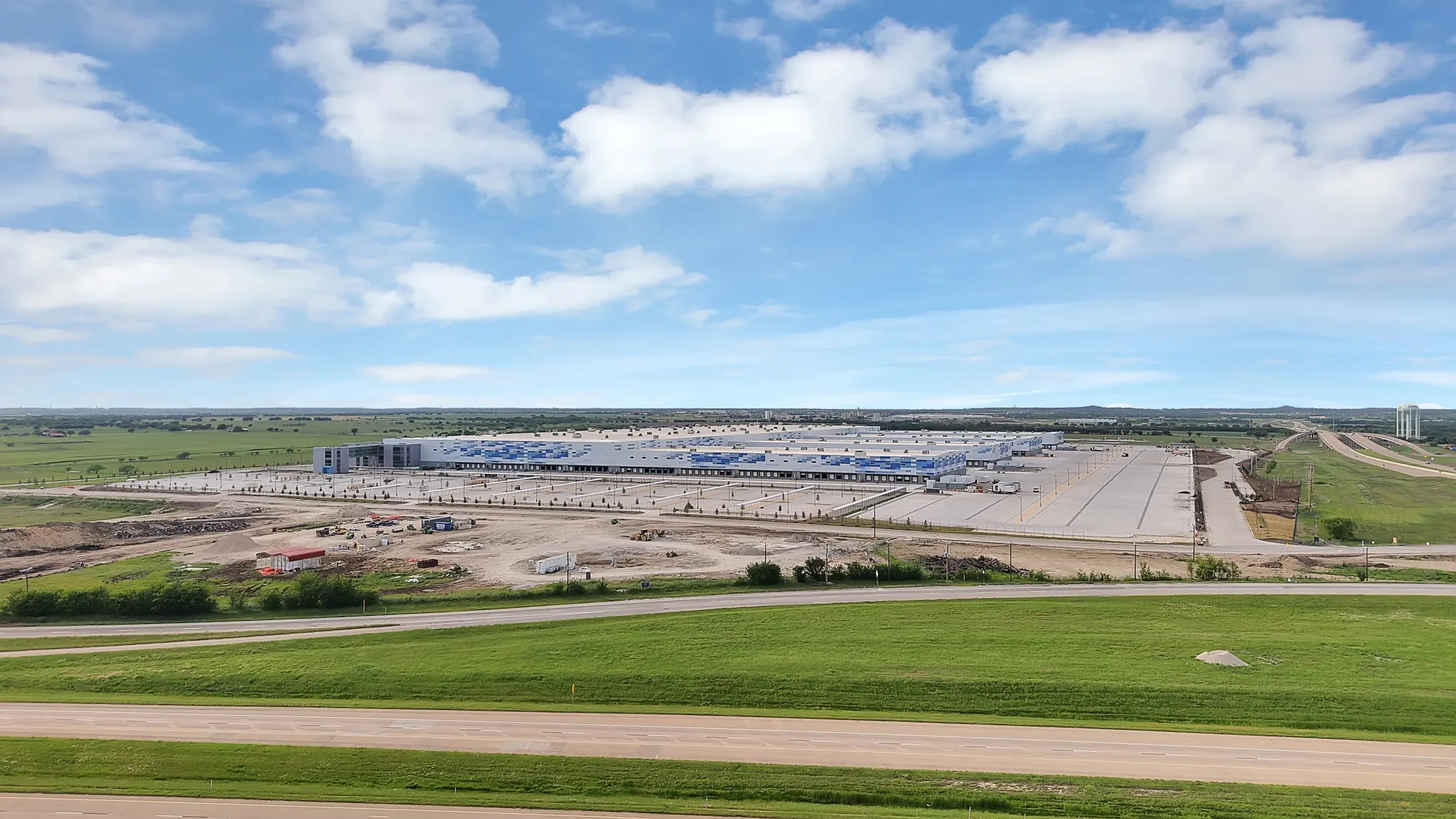 Expansive commercial development featuring multiple large structures, extensive paved areas, and a substantial parking facility