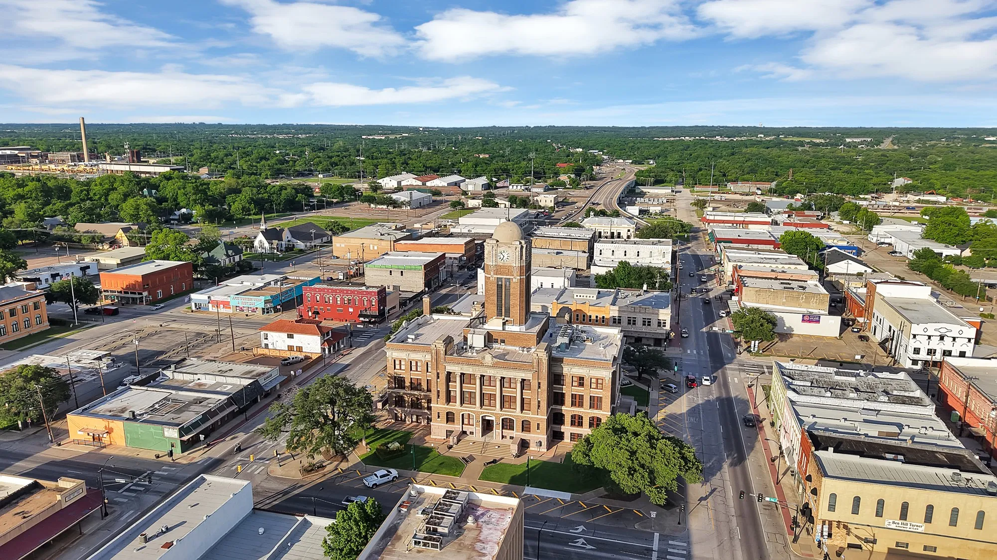 Aerial perspective of a town square featuring a prominent clock tower building