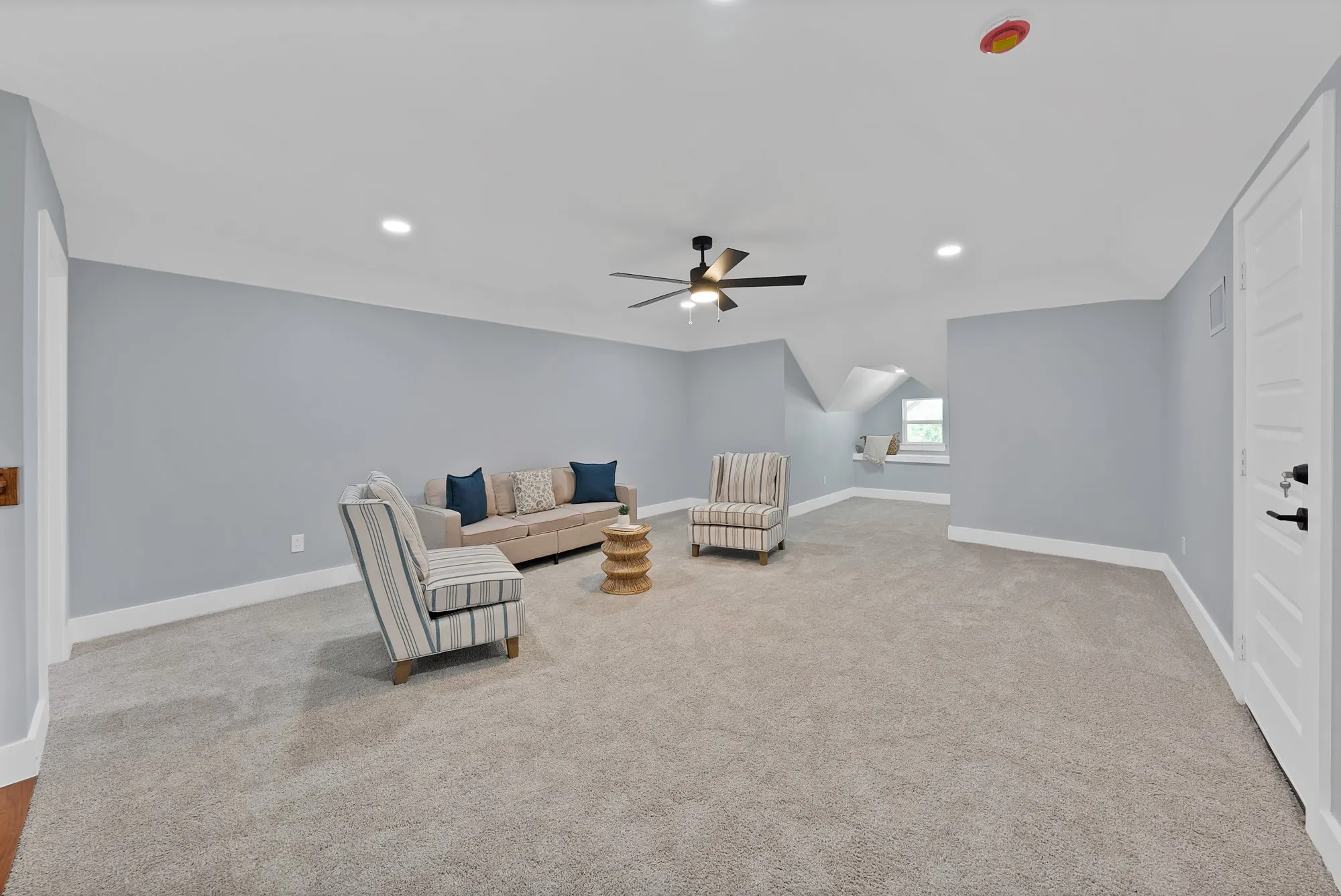 Spacious carpeted room featuring a ceiling fan, recessed lighting, and an architectural dormer window with a built-in ledge