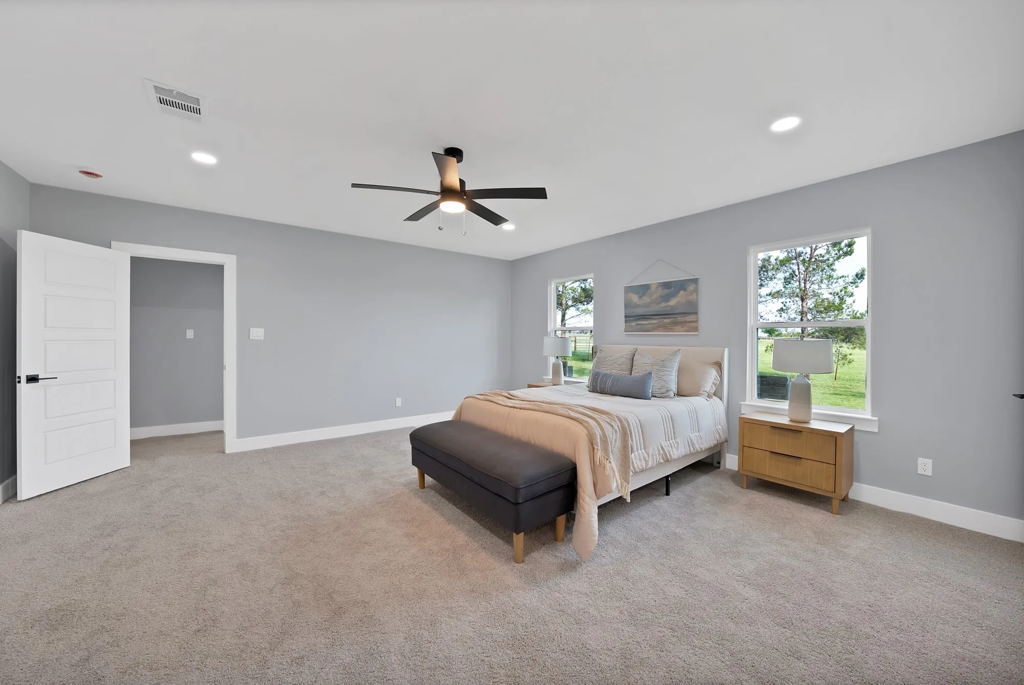 Light gray walls complement the neutral carpeting in this room, featuring recessed lighting and a ceiling fan