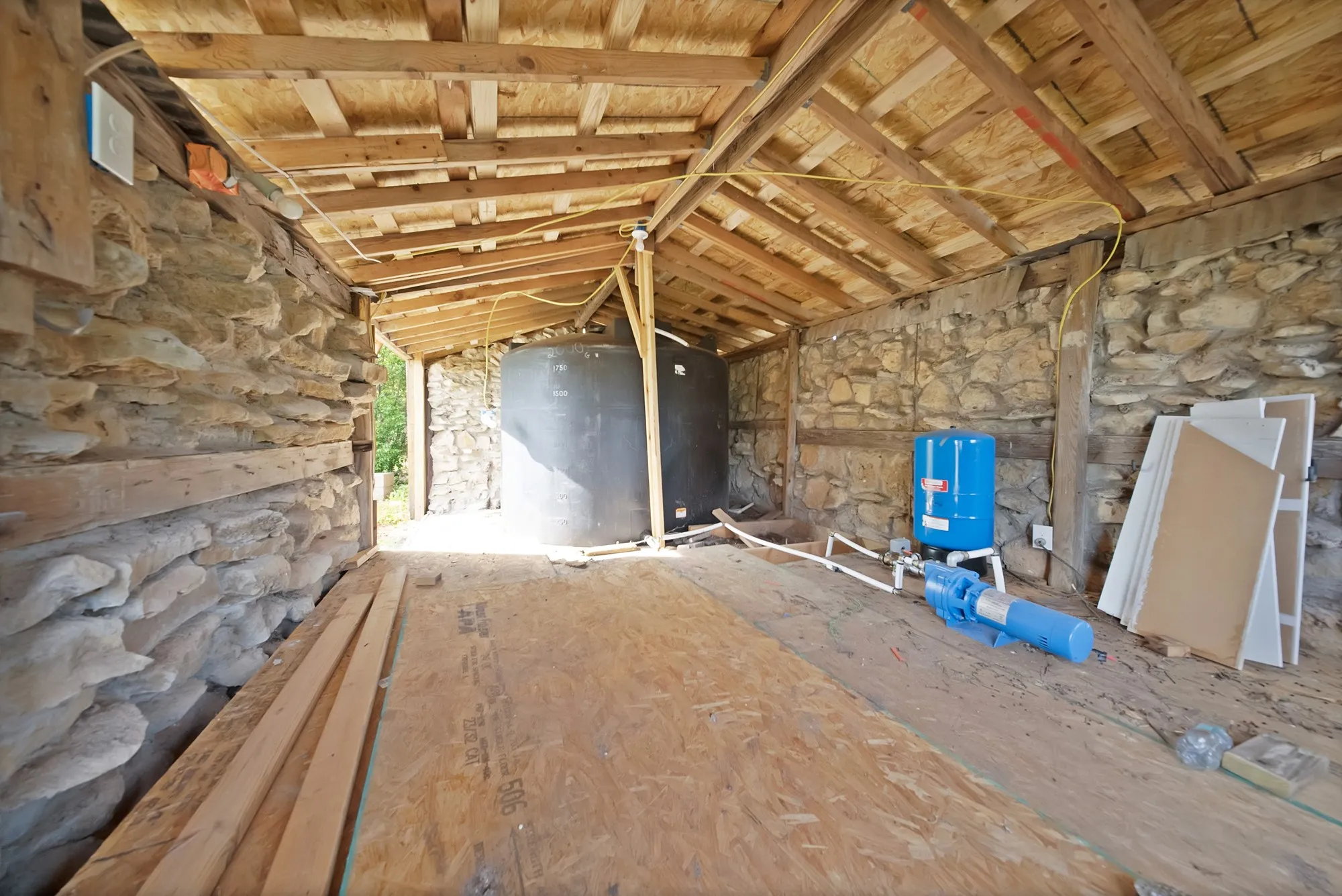 Open-air structure featuring exposed wood beam framing and natural stone walls