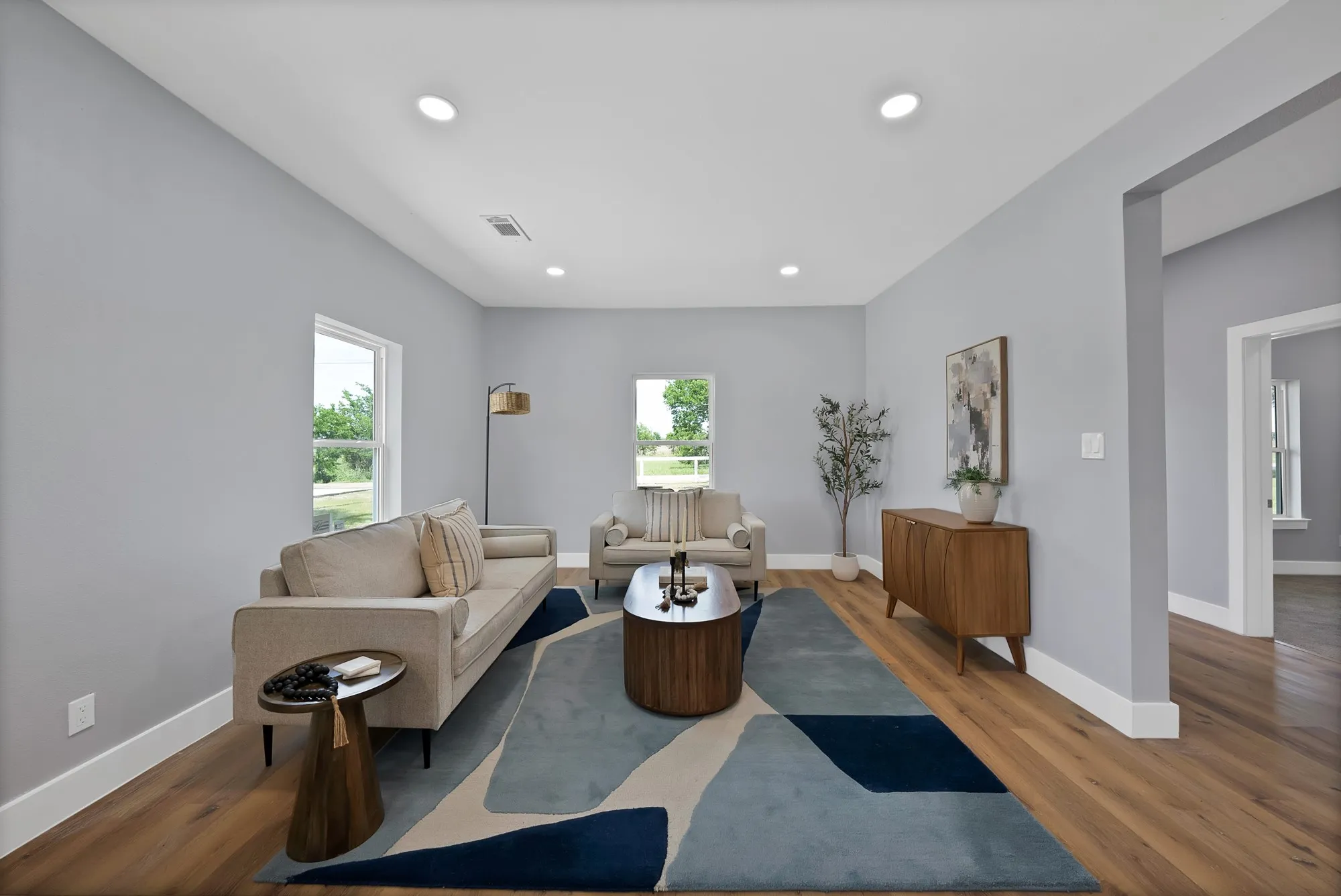 Spacious living area featuring light gray walls, recessed lighting, wood-finish flooring, and white trim