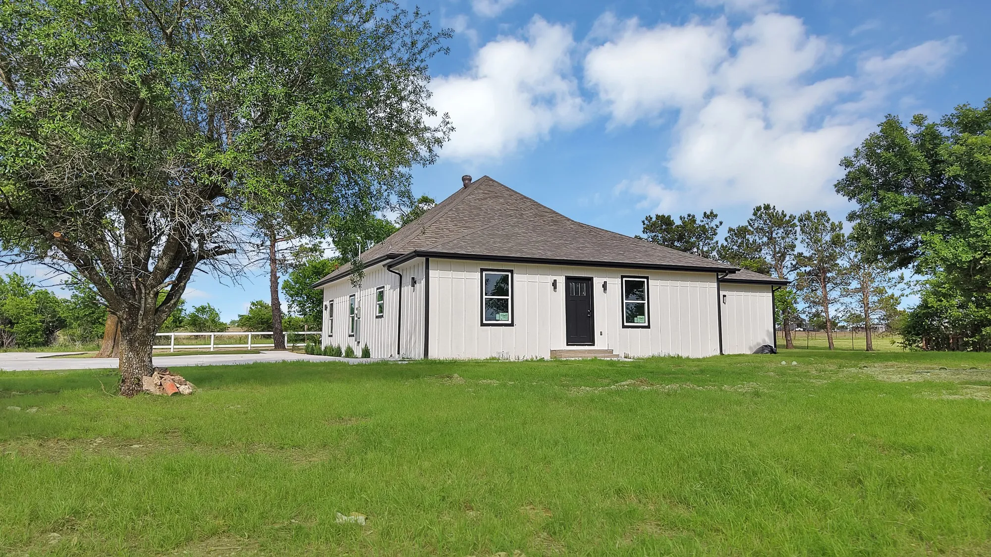 Contemporary single-story residence featuring white vertical siding with dark trim accents