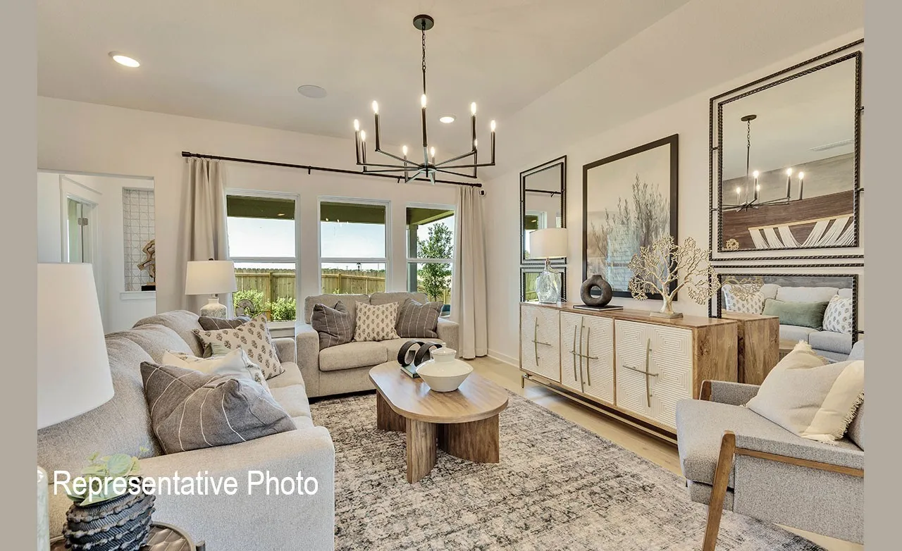 Spacious living area featuring light wood-finish flooring, a contemporary chandelier, multiple large windows, and a built-in wall cabinet with integrated shelving