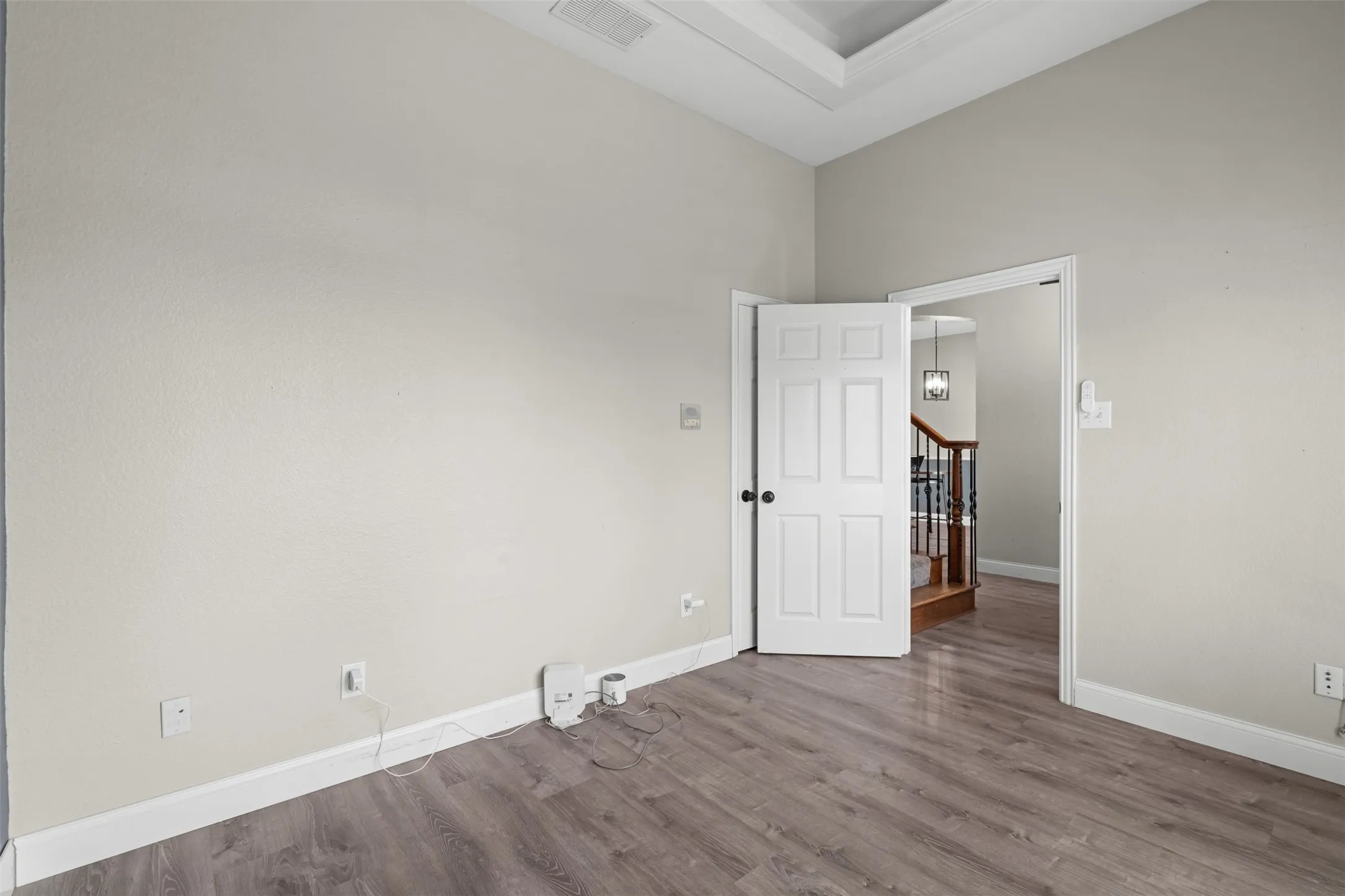 Downstairs Neutral-toned interior room with wood-finish flooring, white baseboards, and a tray ceiling