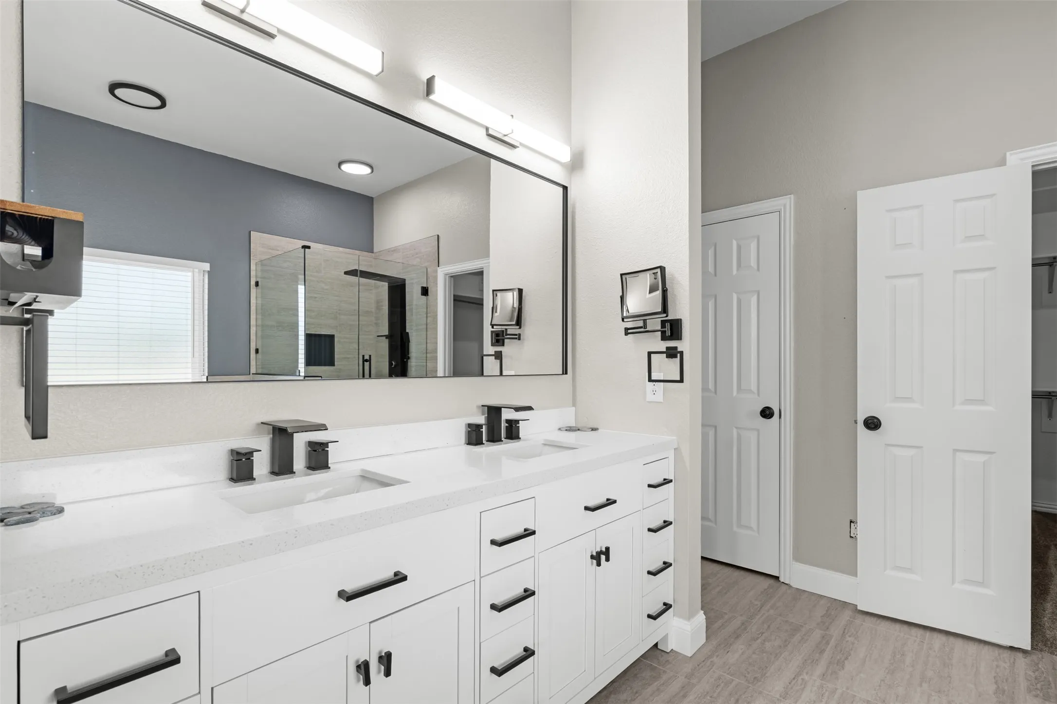 Dual vanity with white shaker-style cabinetry, matte black hardware, and integrated sinks