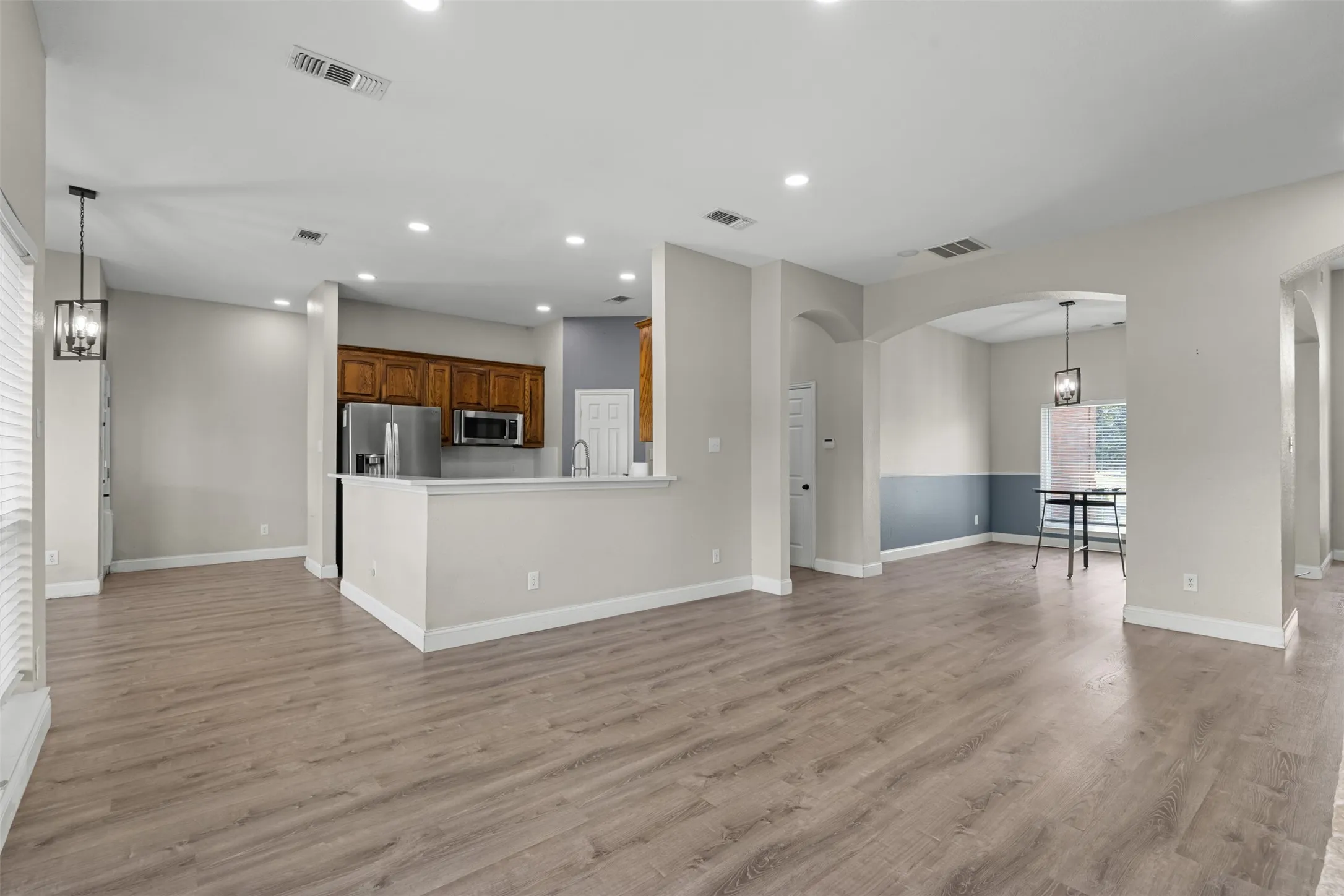Open-concept interior featuring wood-finish flooring, recessed lighting, and arched doorways