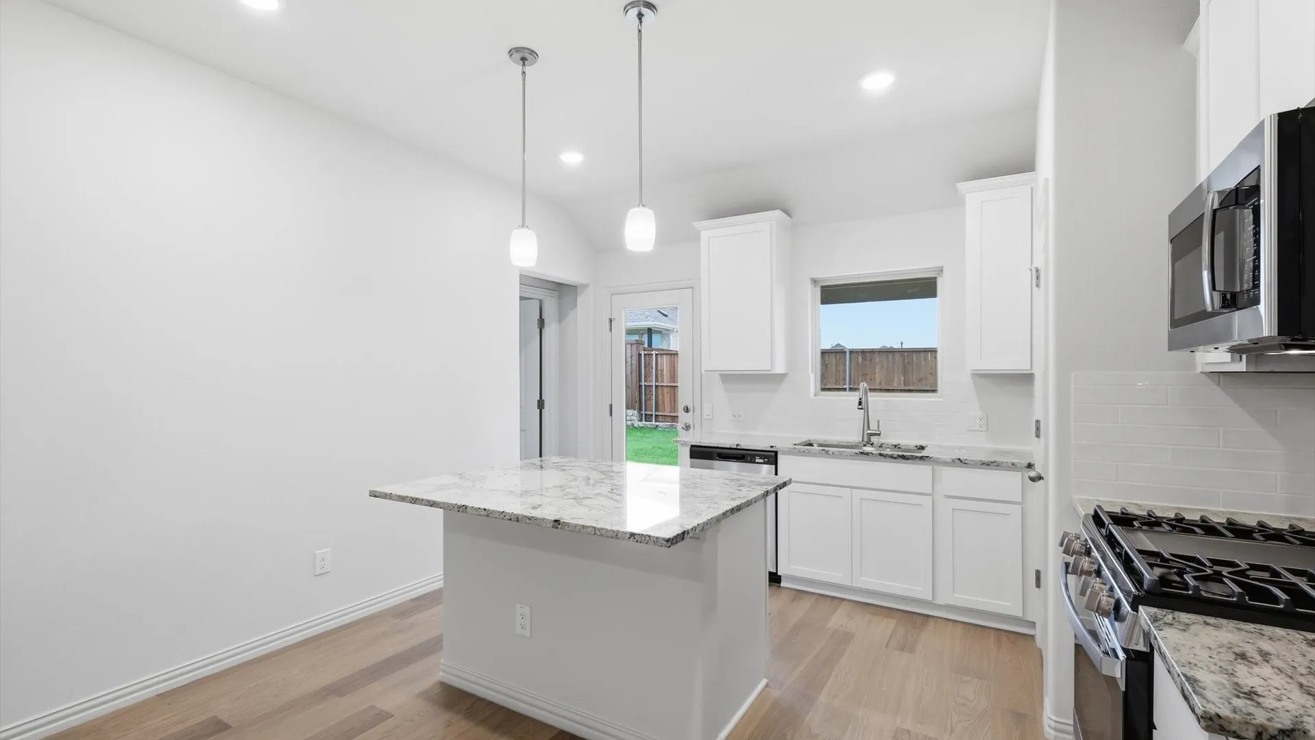 Modern kitchen featuring a central island with a granite countertop, white cabinetry, stainless steel appliances, and wood-finish flooring