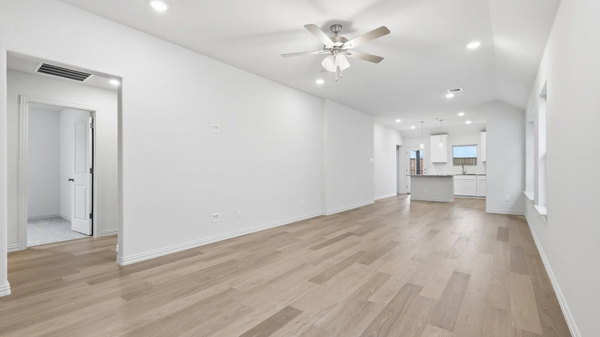 Spacious living area featuring wood-finish flooring, recessed lighting, a ceiling fan, and white baseboards