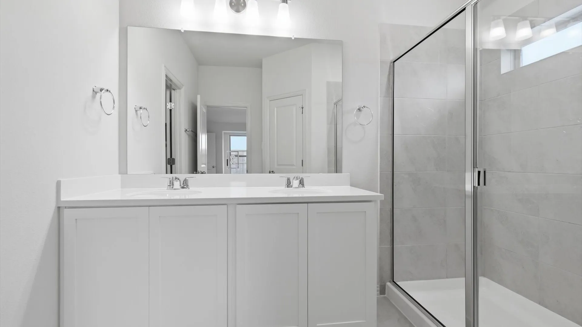 Dual vanity with white cabinetry, integrated sinks, chrome fixtures, and a large wall-mounted mirror