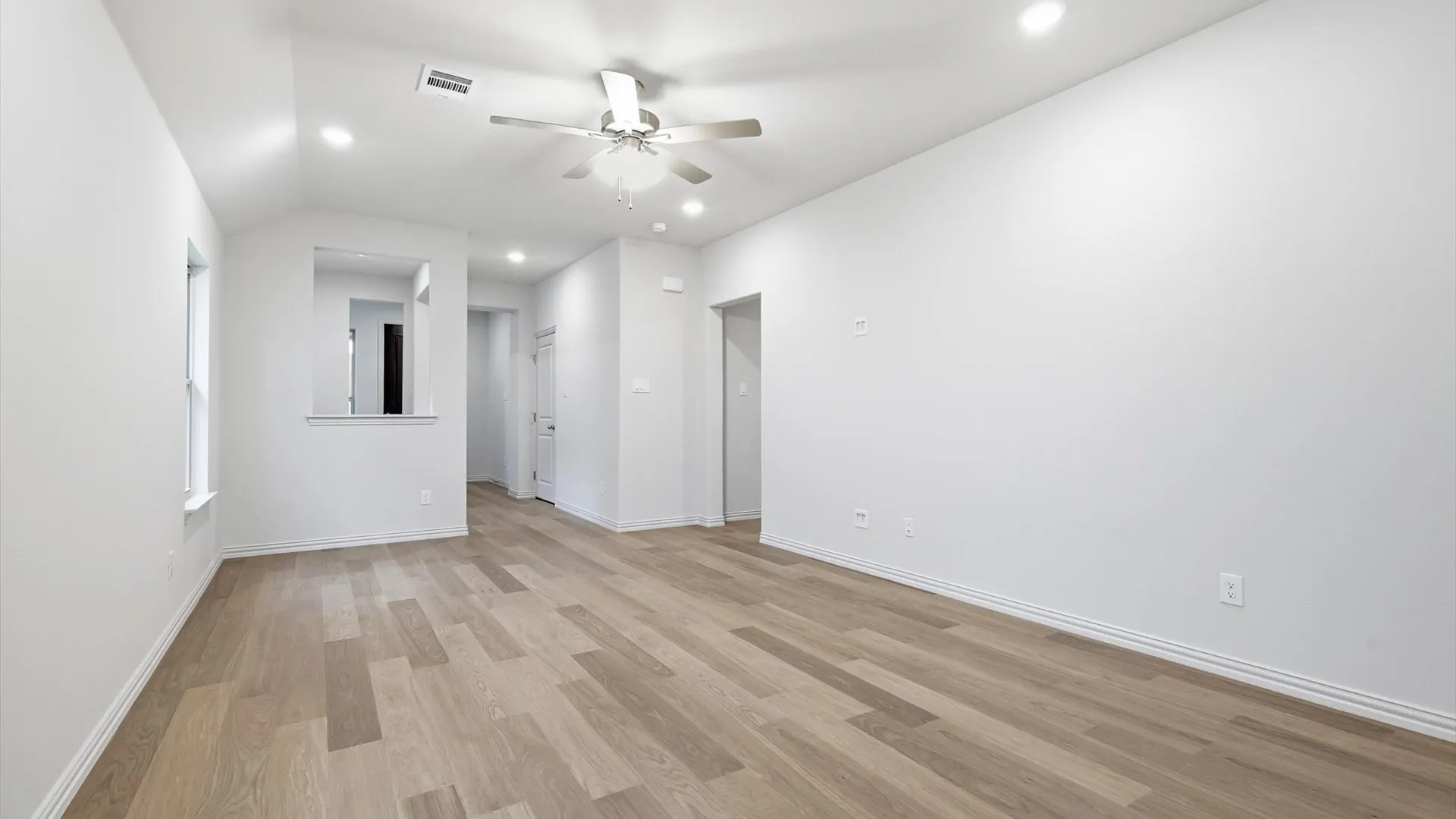 Spacious room featuring wood-finish flooring, recessed lighting, and a ceiling fan