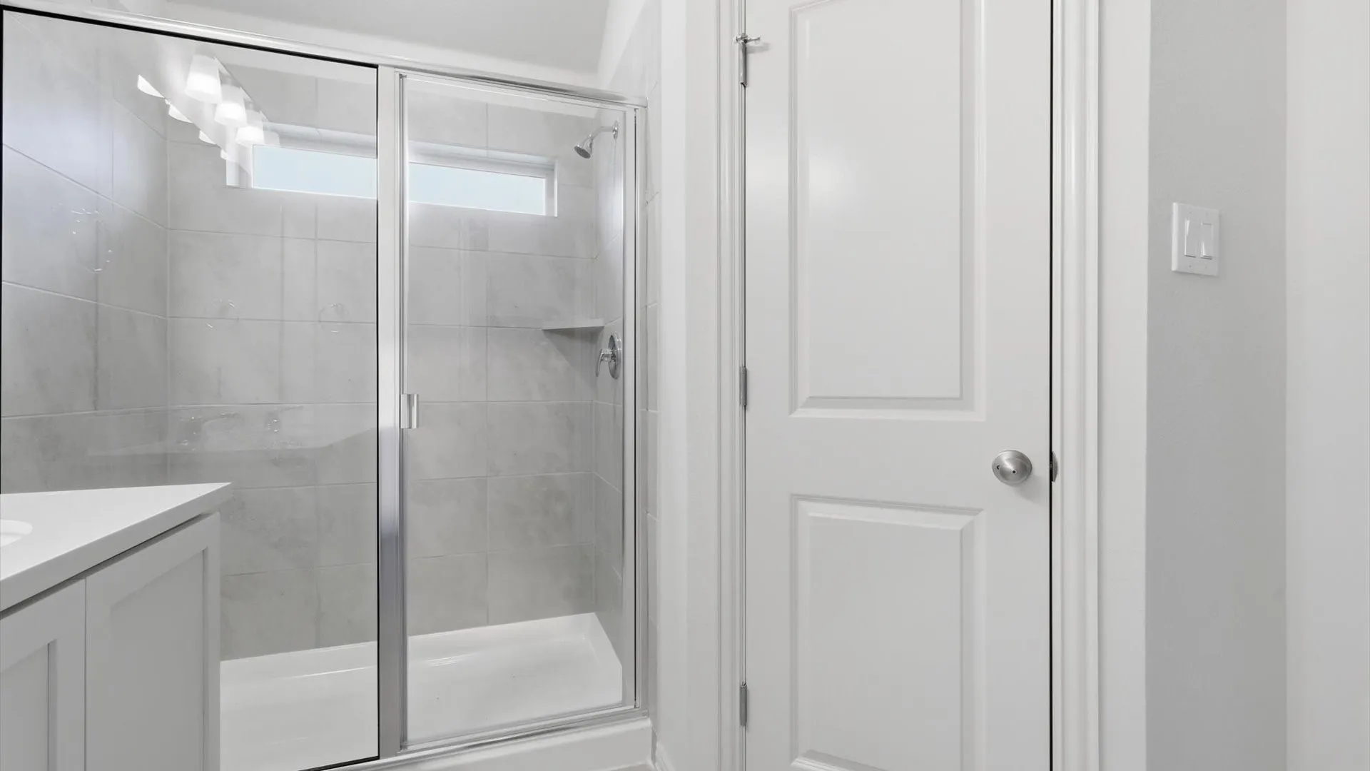 Shower enclosure featuring a sliding glass door, tiled walls, and a built-in shelf