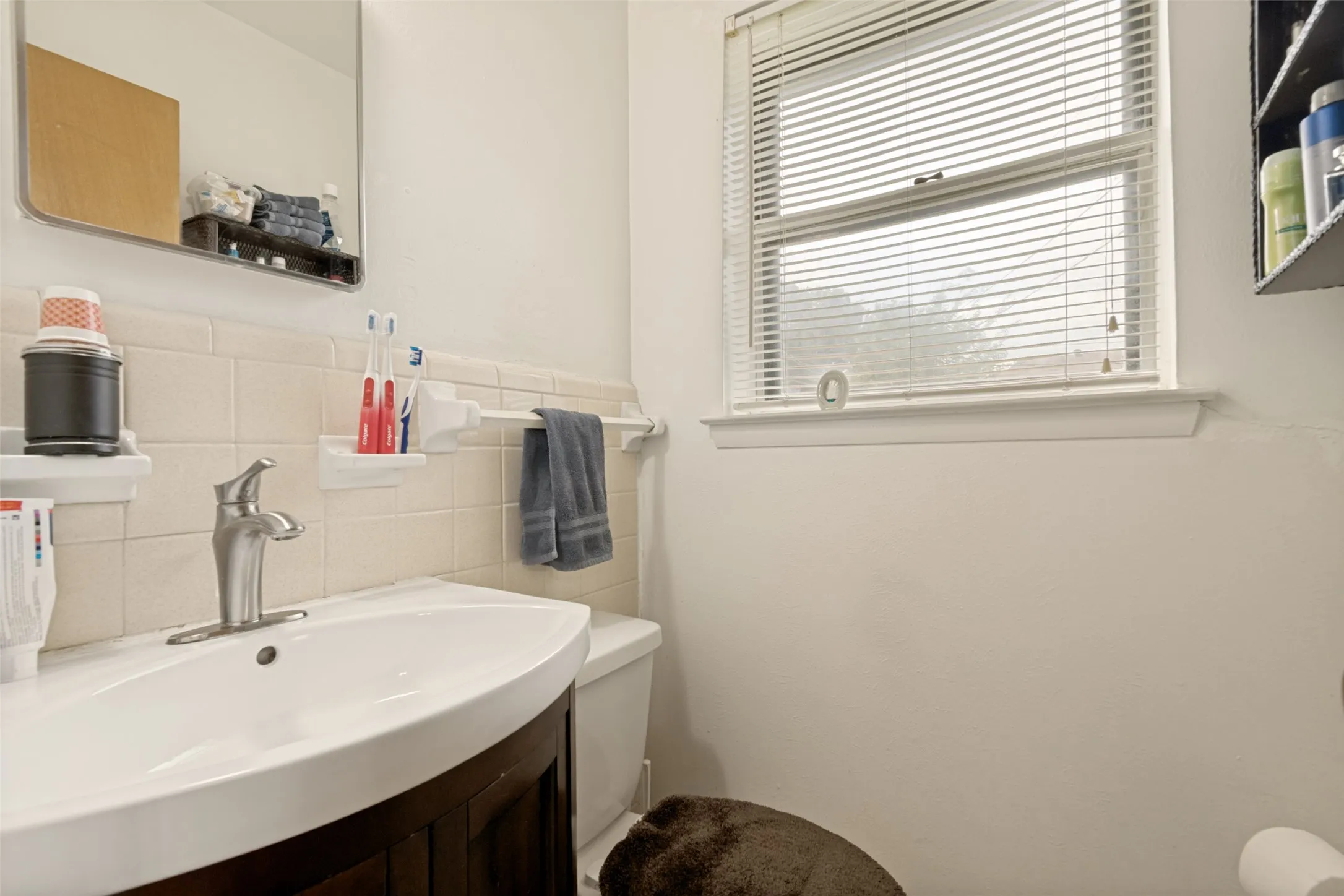 White vanity with integrated sink, brushed nickel faucet, and tiled backsplash
