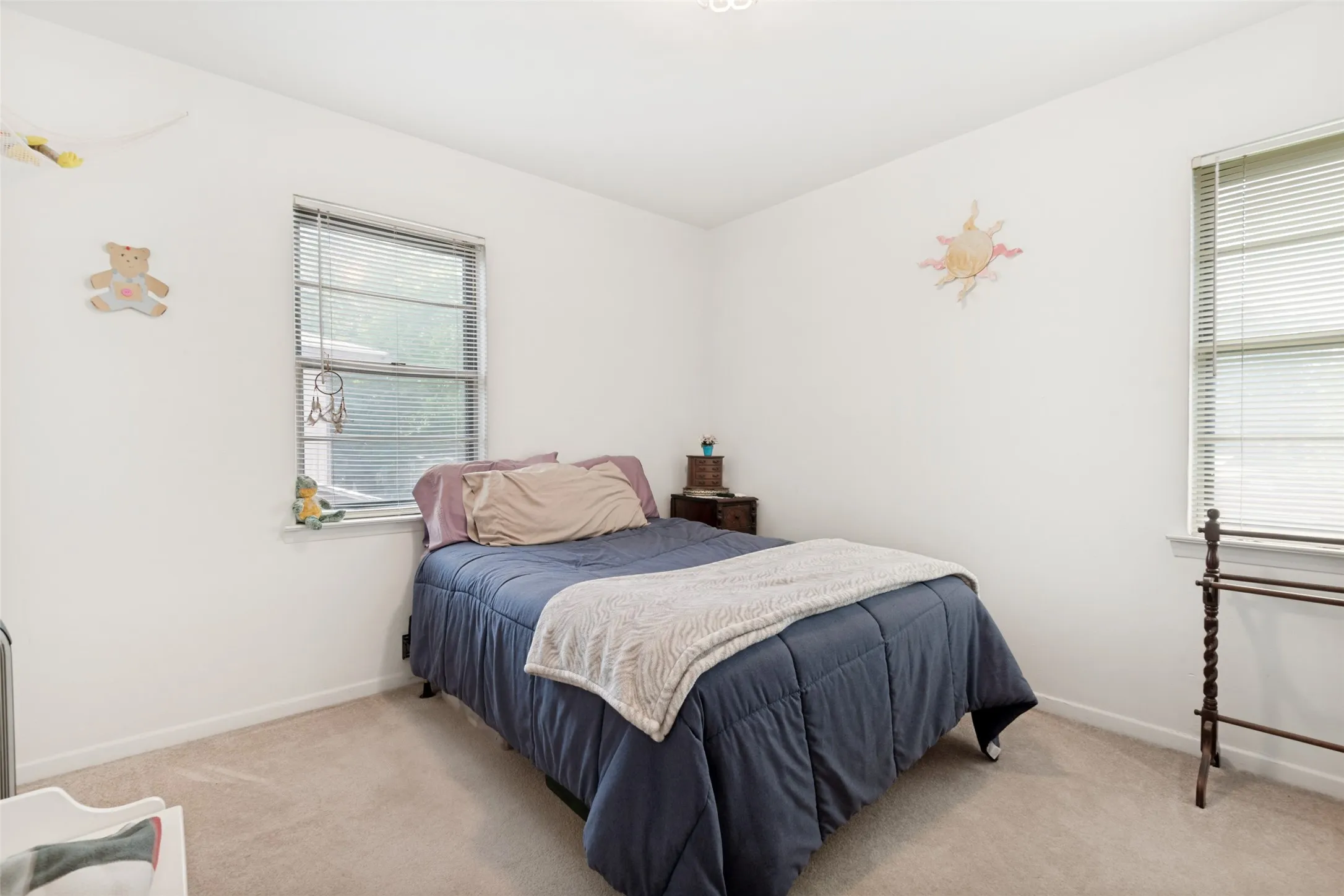 Carpeted room featuring two windows with horizontal blinds, white walls, and a ceiling light fixture
