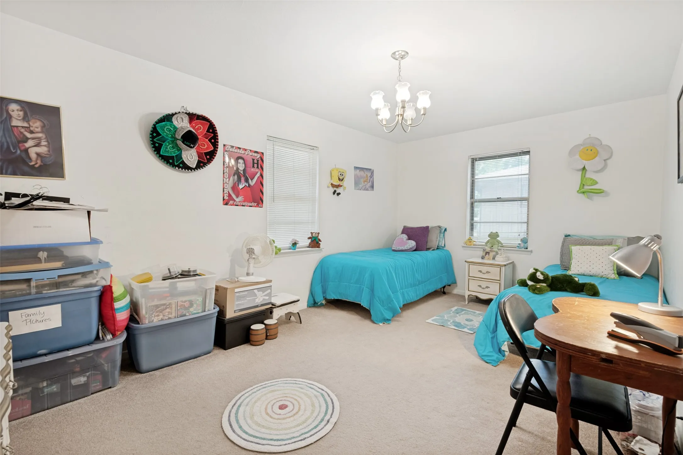 Bright room featuring a ceiling-mounted chandelier, carpeted flooring, and two windows providing natural light