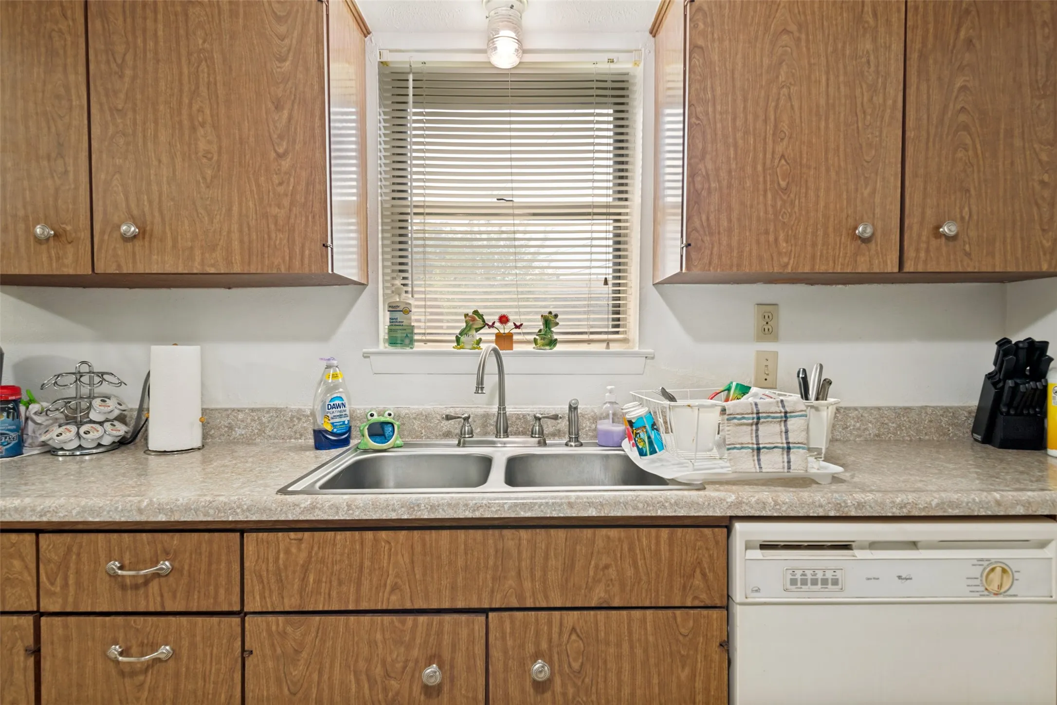 Kitchen featuring wood-finish cabinetry, a double-basin stainless steel sink, and laminate countertops