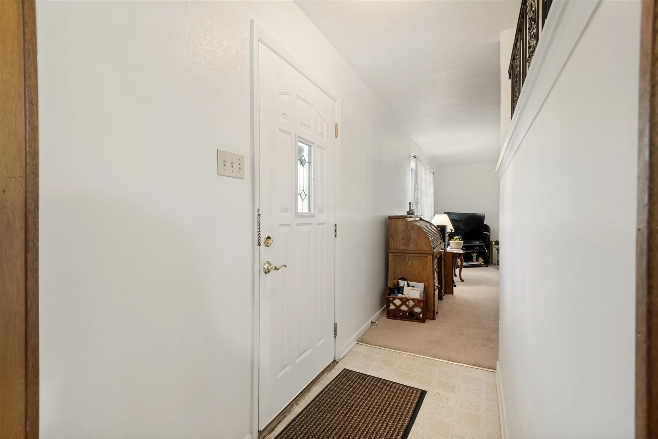 Entryway with a paneled white door featuring a decorative glass insert and brass hardware